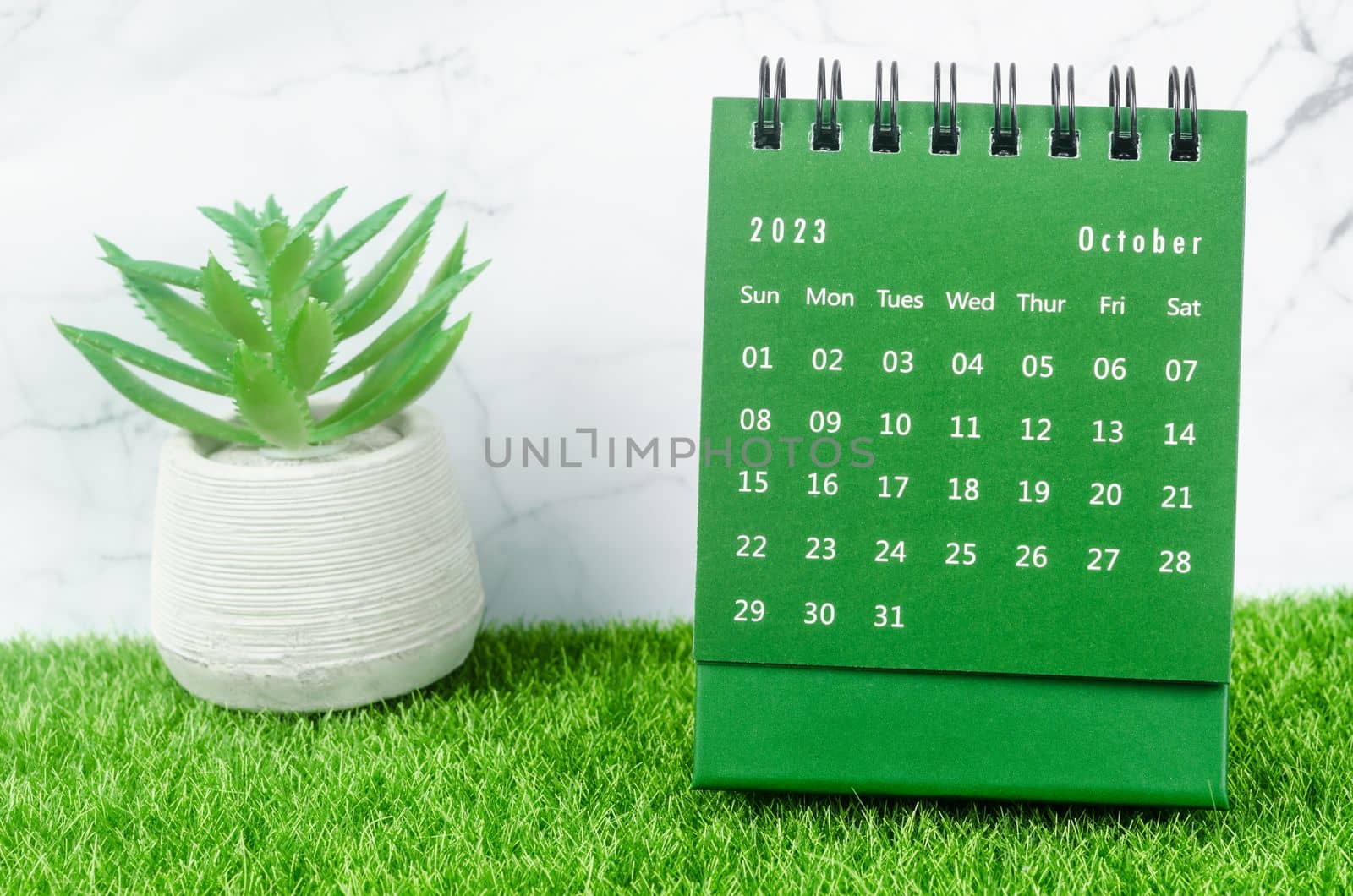 Green October 2023 Monthly desk calendar for 2023 year on grass.