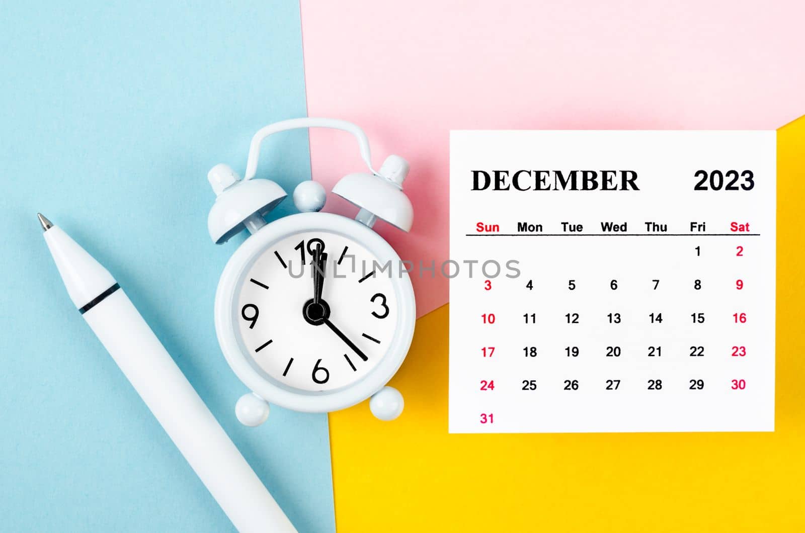 December 2023 Monthly calendar with alarm clock and pen on beautiful background.