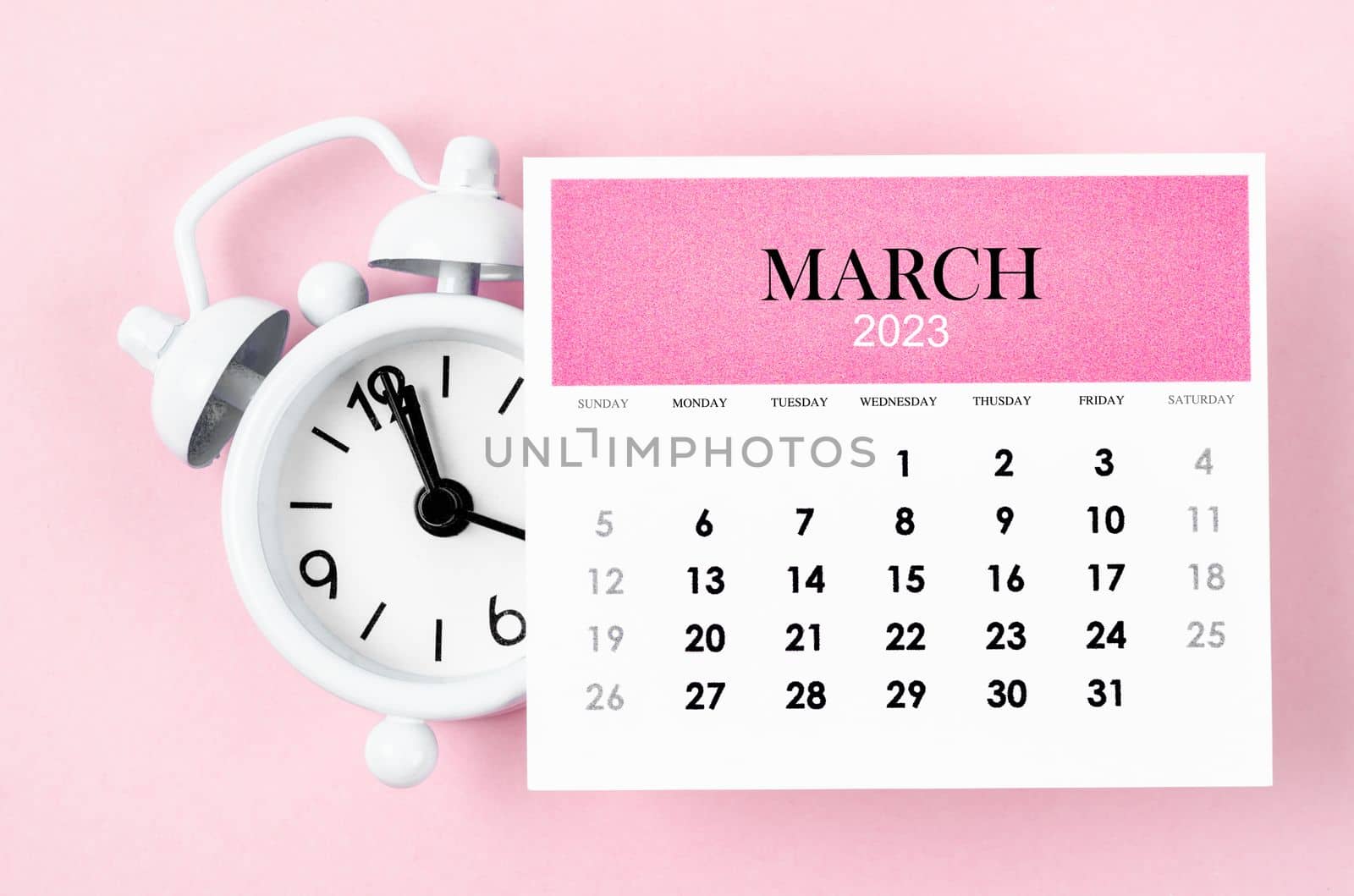 March 2023 Monthly calendar year with alarm clock on pink colour background.