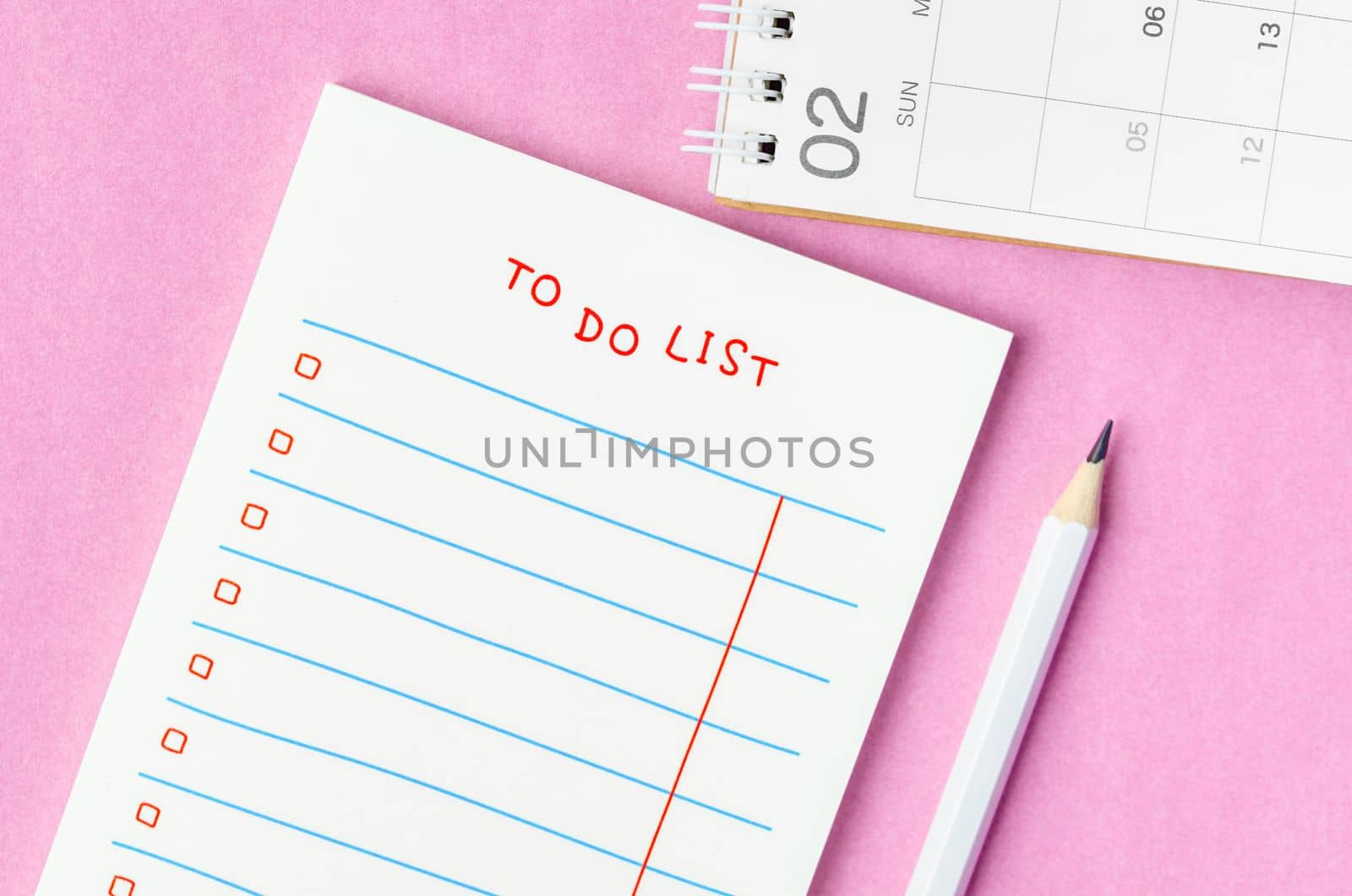 Blank To do list in notepad and desk calendar with wooden pencil on pink background. Top view