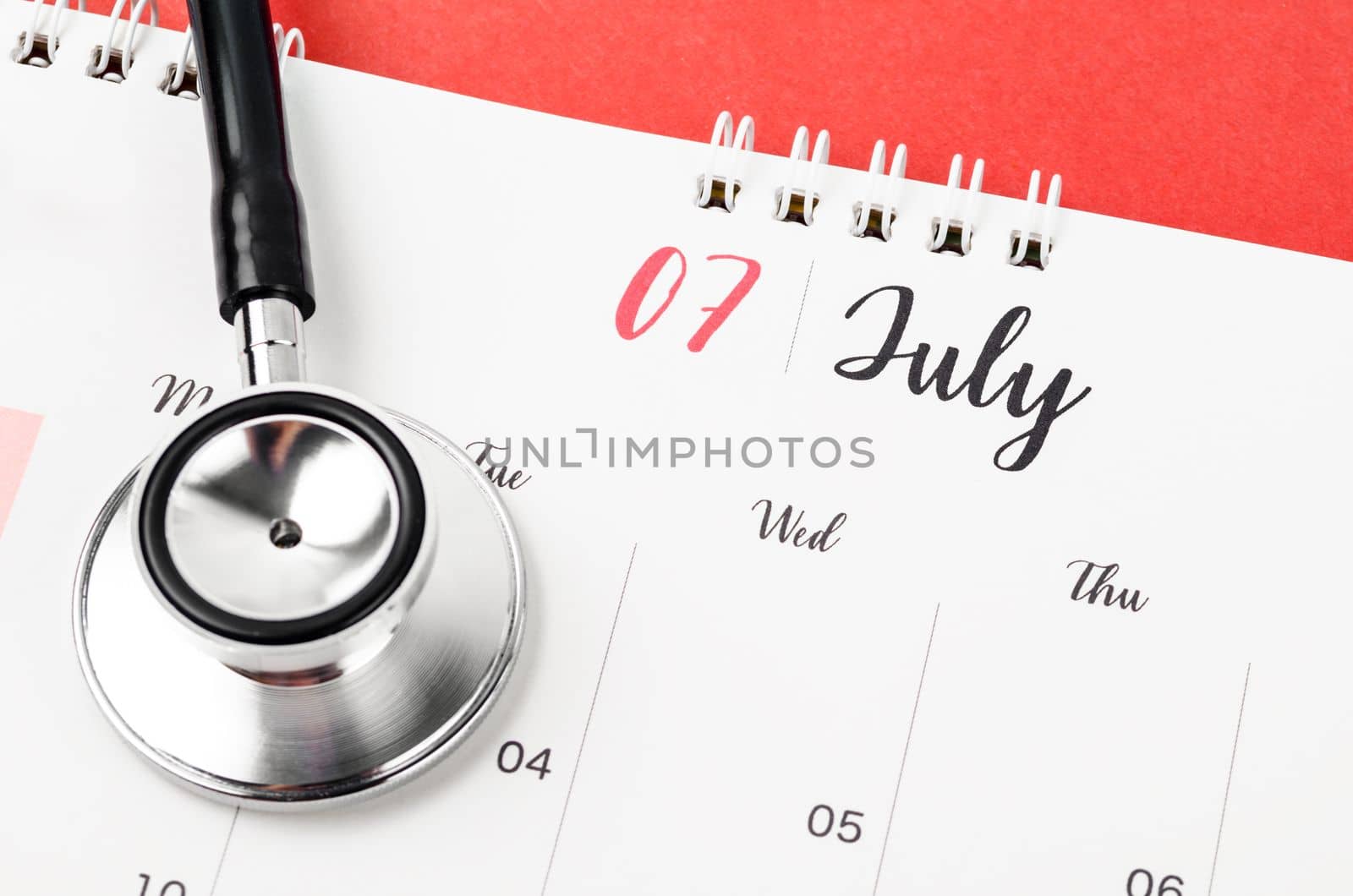 Stethoscope medical and July 2023 desk calendar on the red background, schedule to check up healthy concepts.