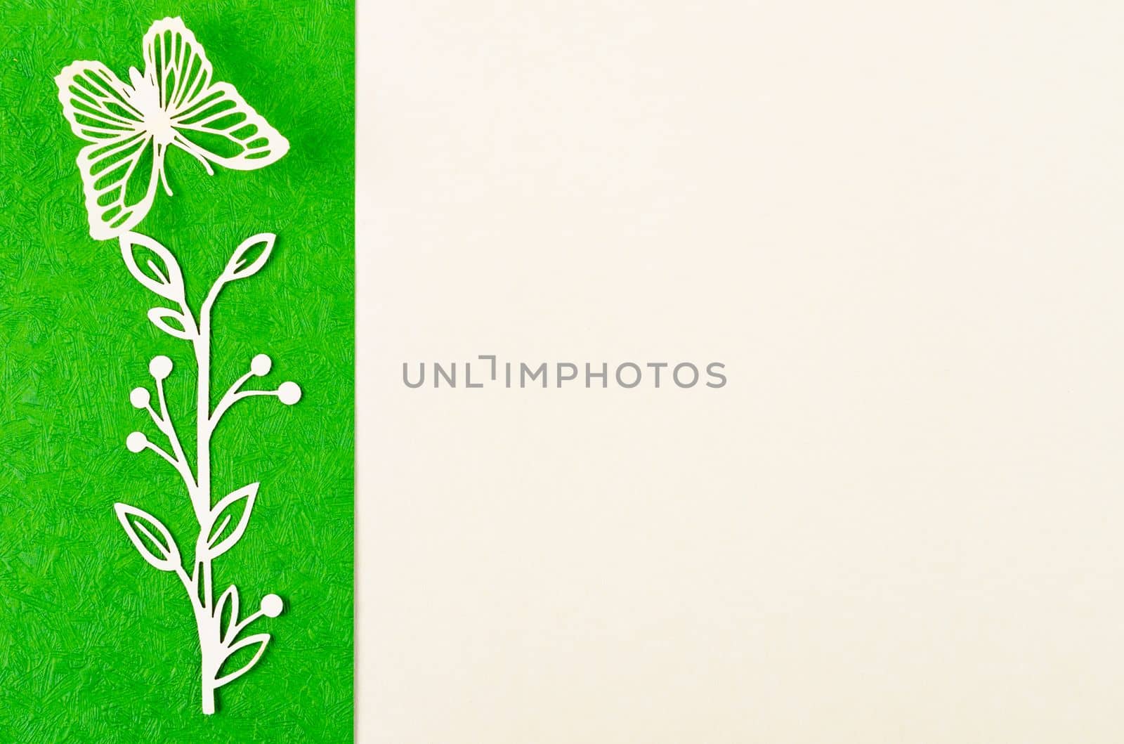 Butterfly and flower made from carve paper or cutting on green and yellow background with empty space for your text or message.
