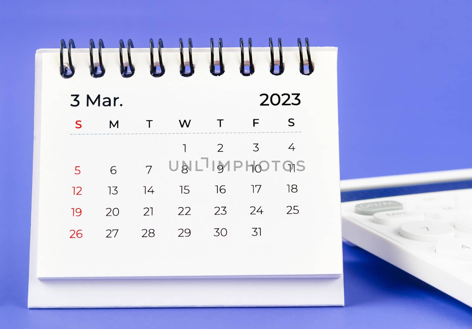 March 2023 Monthly desk calendar for 2023 year with calculator on purple background.