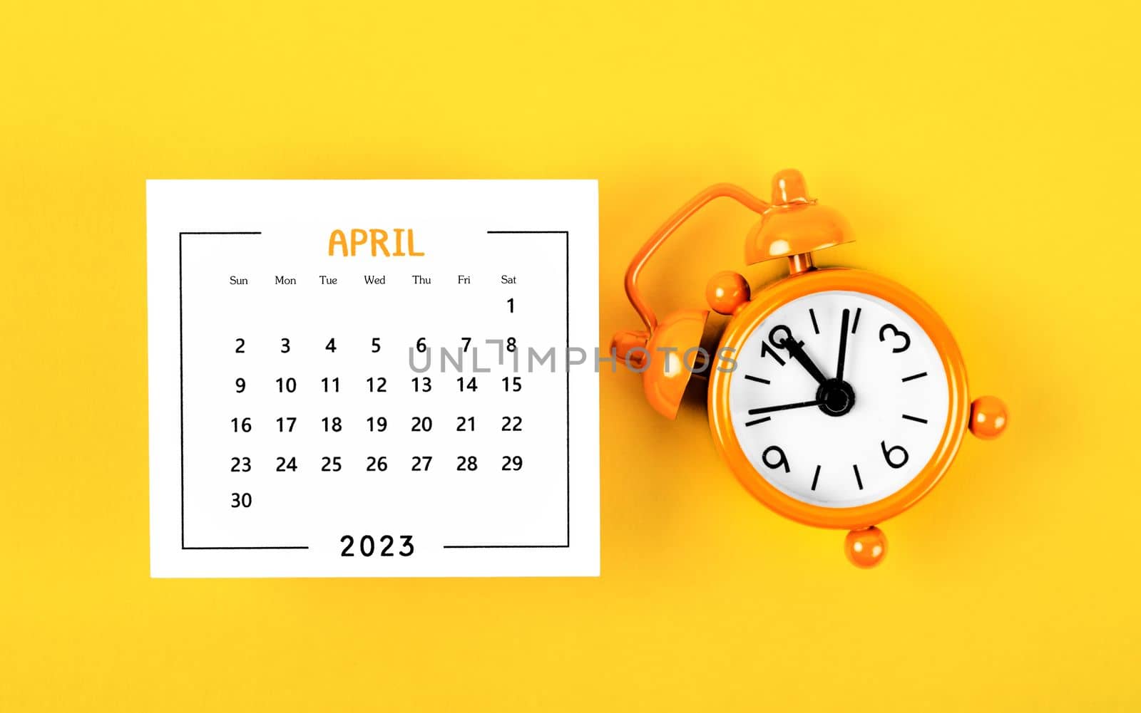 April 2023 Monthly calendar for 2023 year with alarm clock on yellow background.
