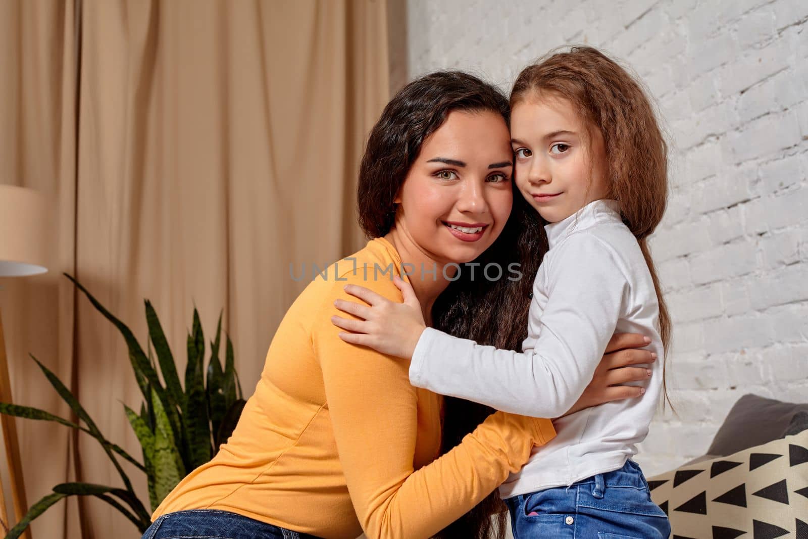 Love of young mother and daughter. They sit on the bed at home and have fun by nazarovsergey