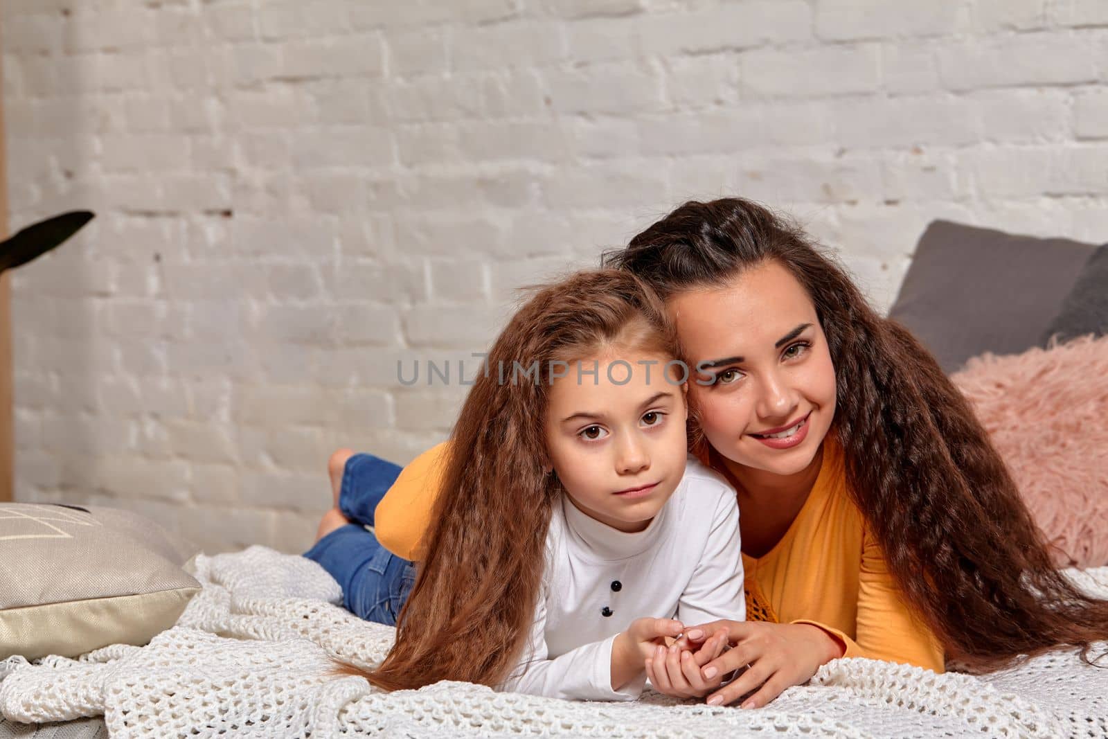 Love of young mother and daughter. They lie on the bed at home and have fun by nazarovsergey