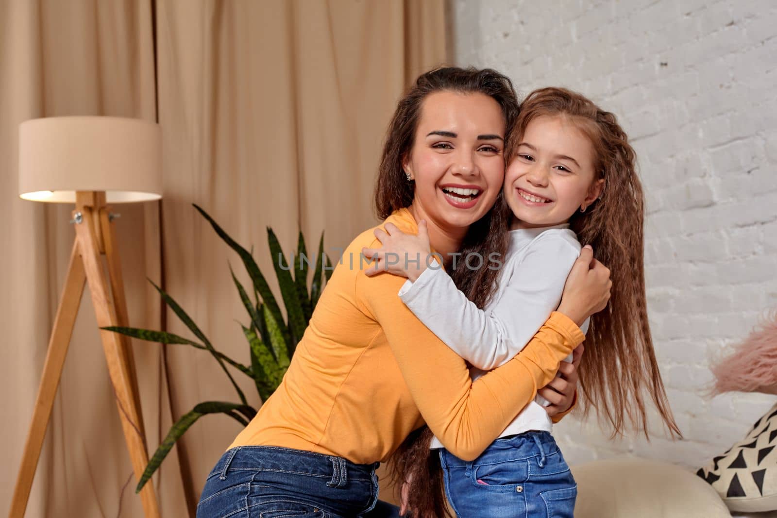 Love of young mother and daughter. They sit on the bed at home and have fun by nazarovsergey