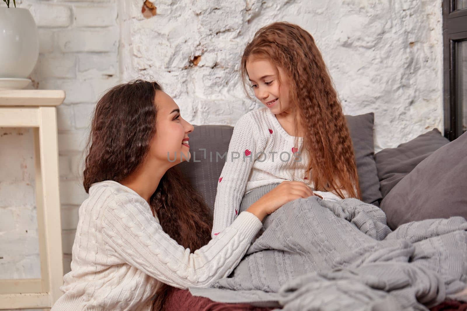 Mother and daughter sitting on sill near window in room by nazarovsergey