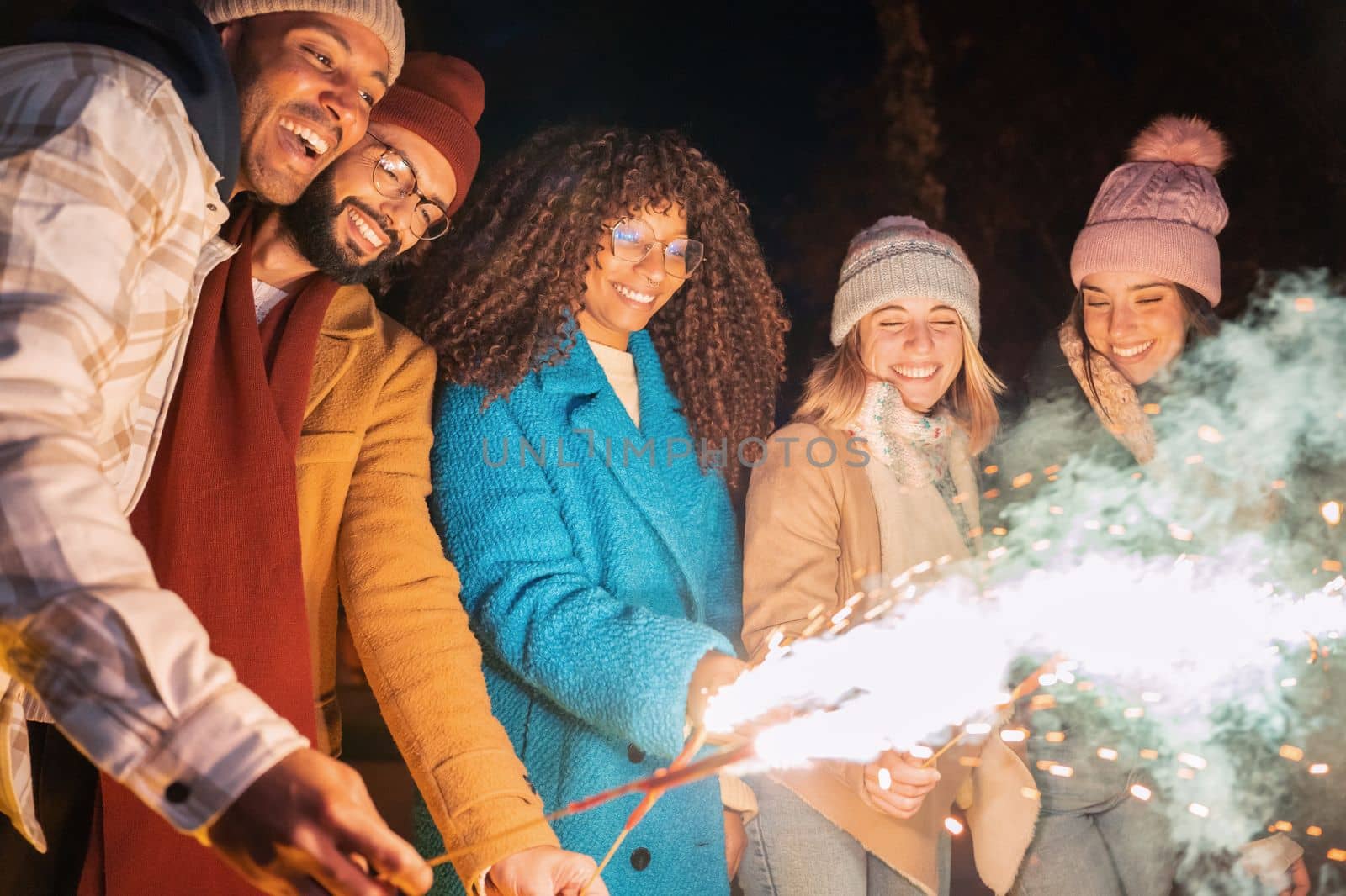 Happy friends enjoying outdoors with sparklers - Group of young people cheerful celebrating with fireworks - Holidays and friendship concept