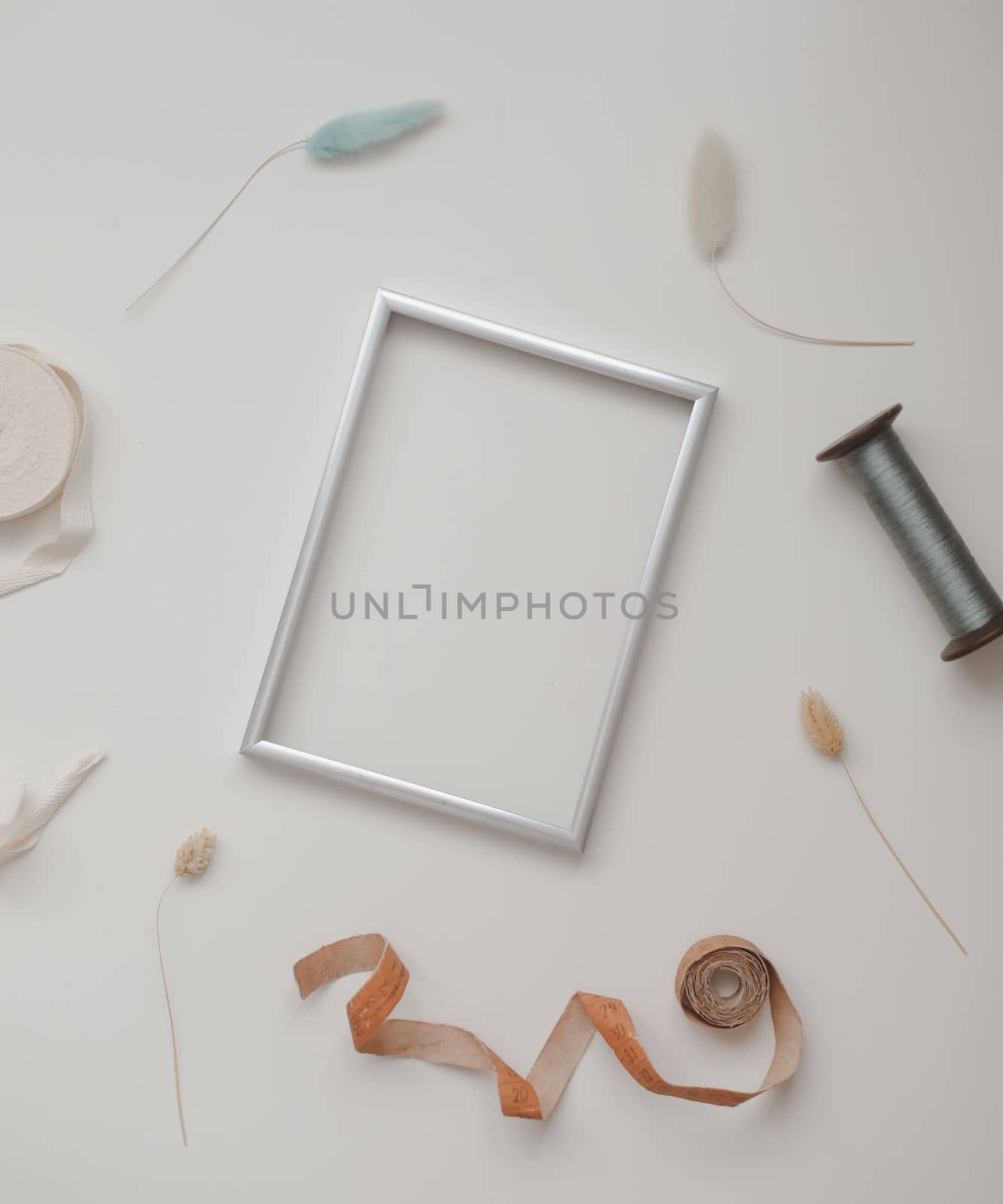 minimal mockup with blank frame with sewing thread and sewing items on white background, flatlay, top view, copy space.