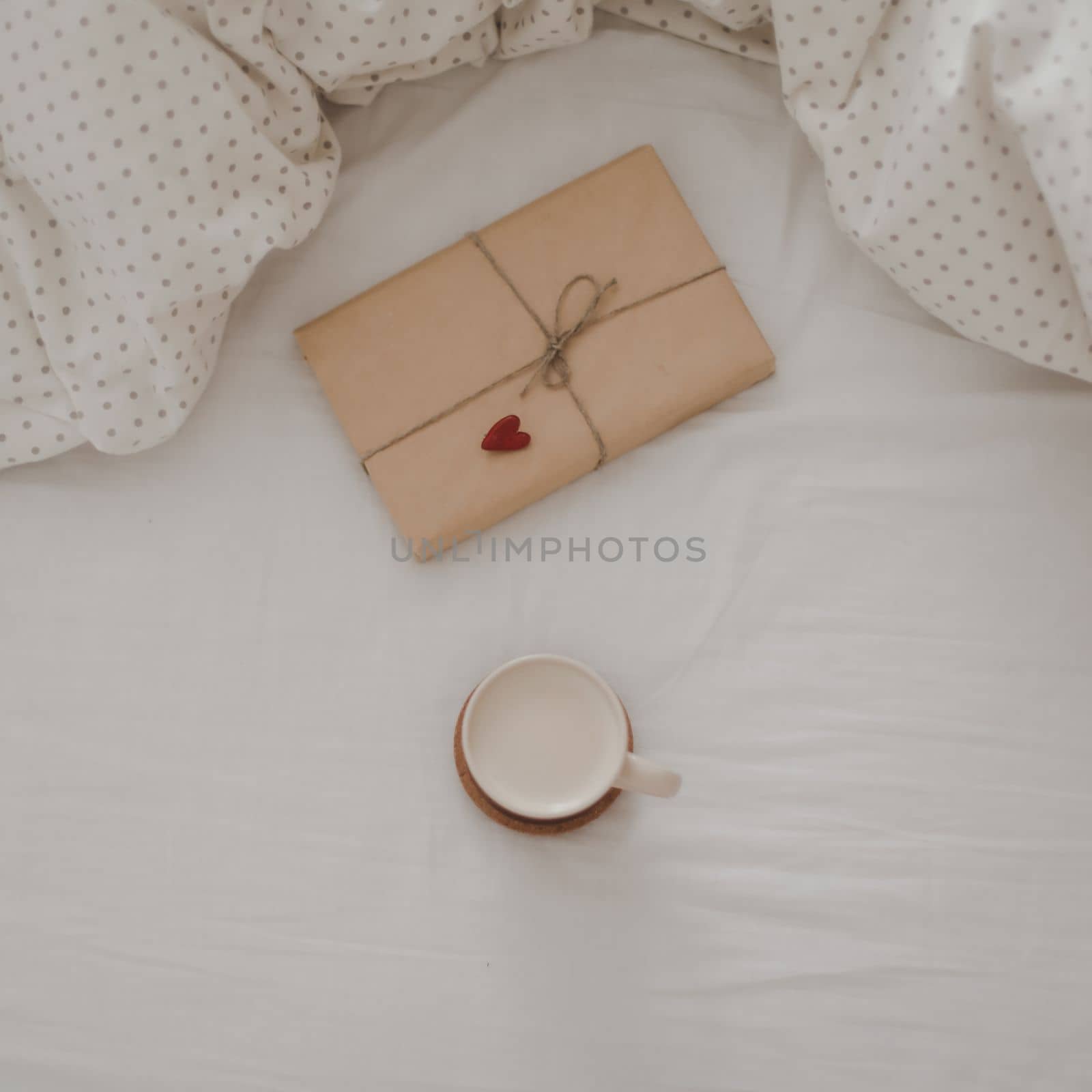 Cup of coffee with milk and gift box in bed with plaid, copy space. Flat lay, top view. morning in bed concept composition. 