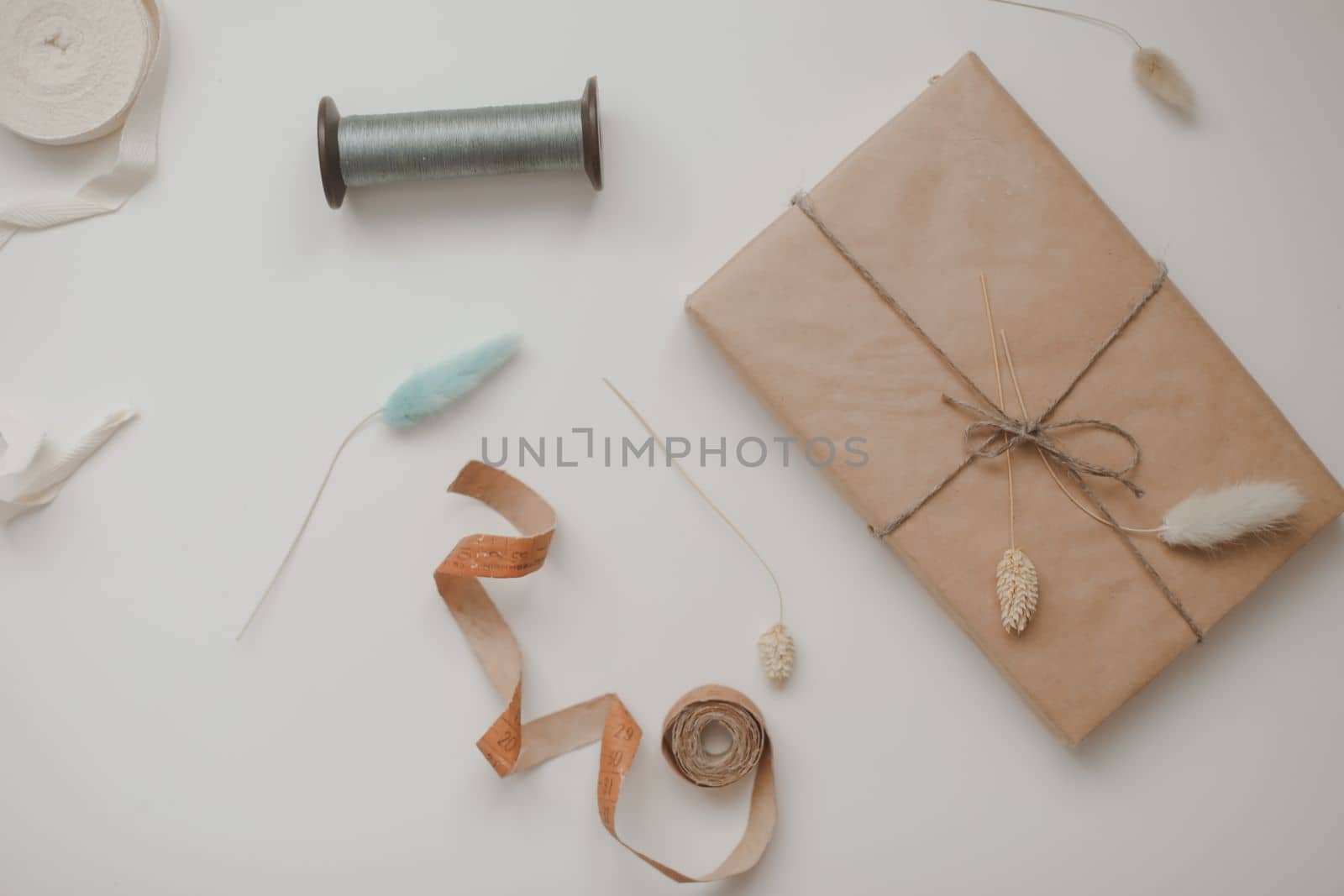 minimal mockup with blank frame with sewing thread and sewing items on white background, flatlay, top view, copy space.