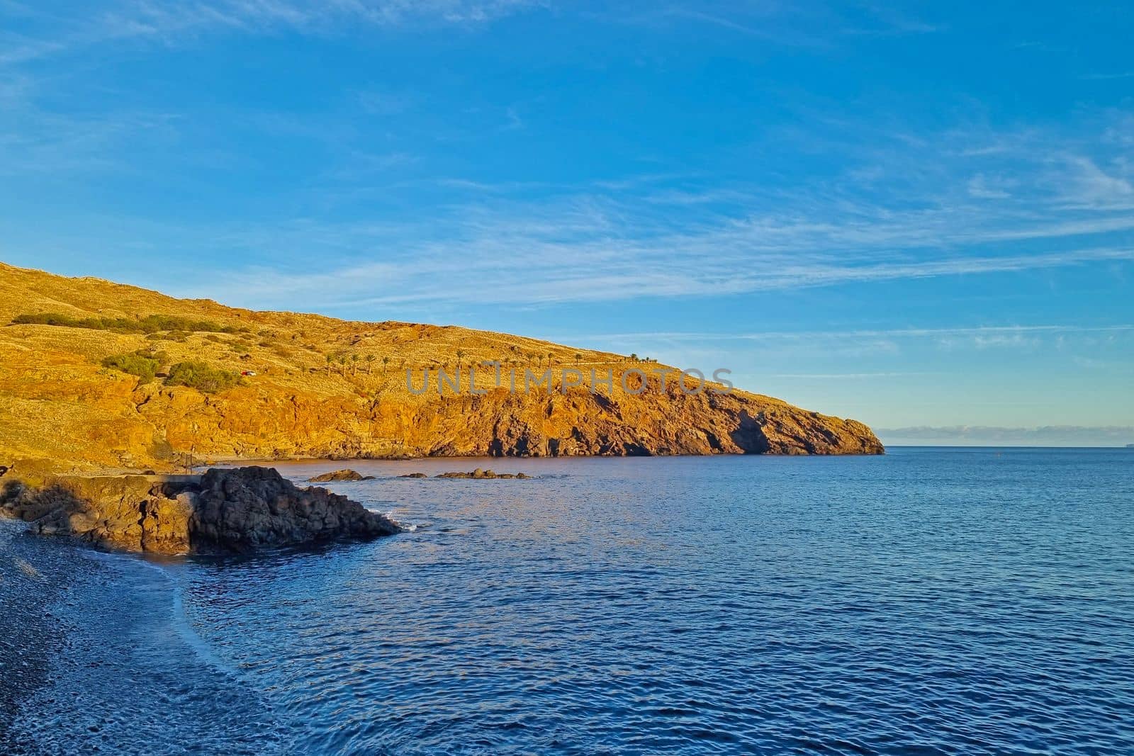 The soft light of the sunset falls on the mountains in the sea or ocean