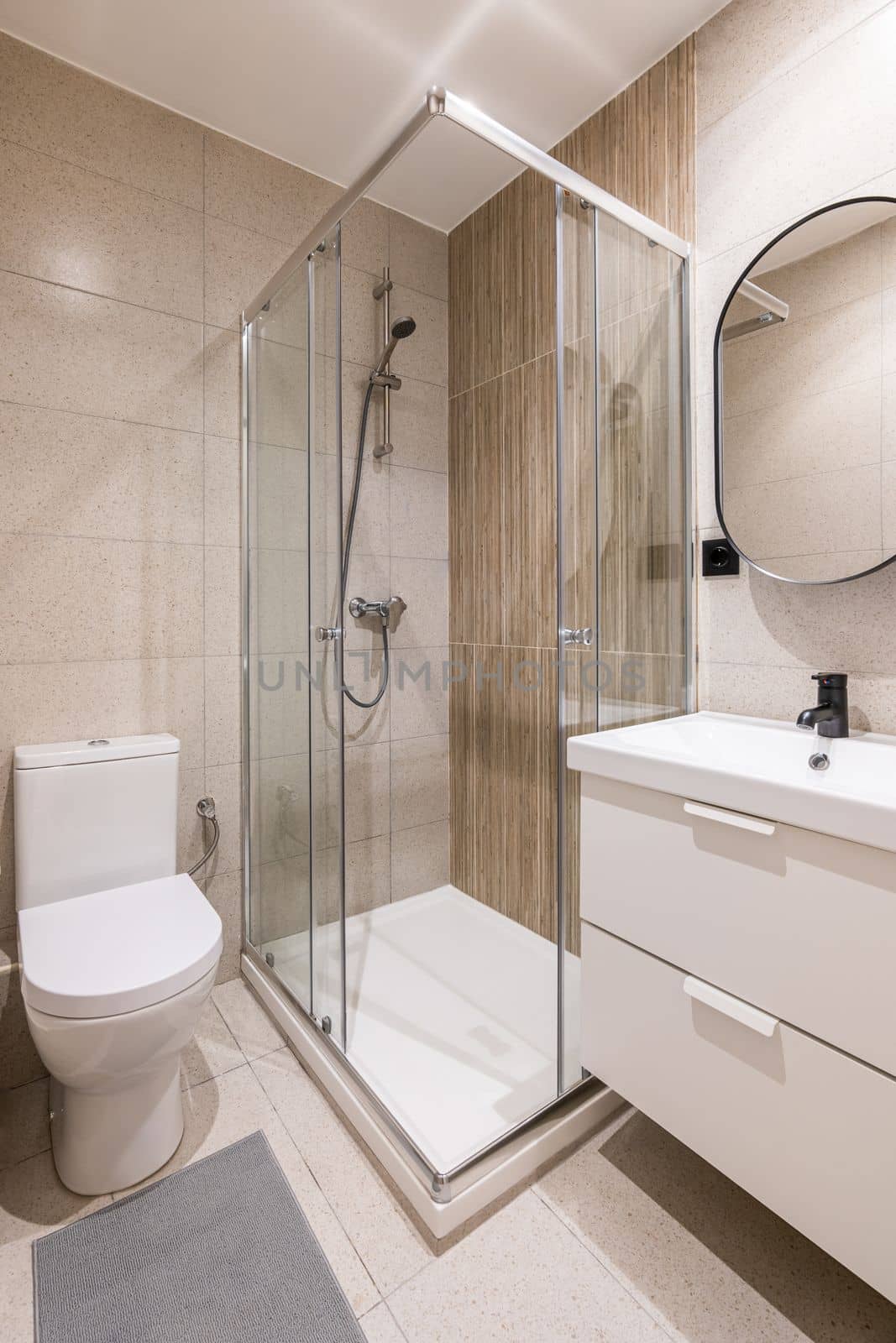 Design of a modern bathroom, with trendy furniture, beige tiles, a modern washbasin and a round mirror