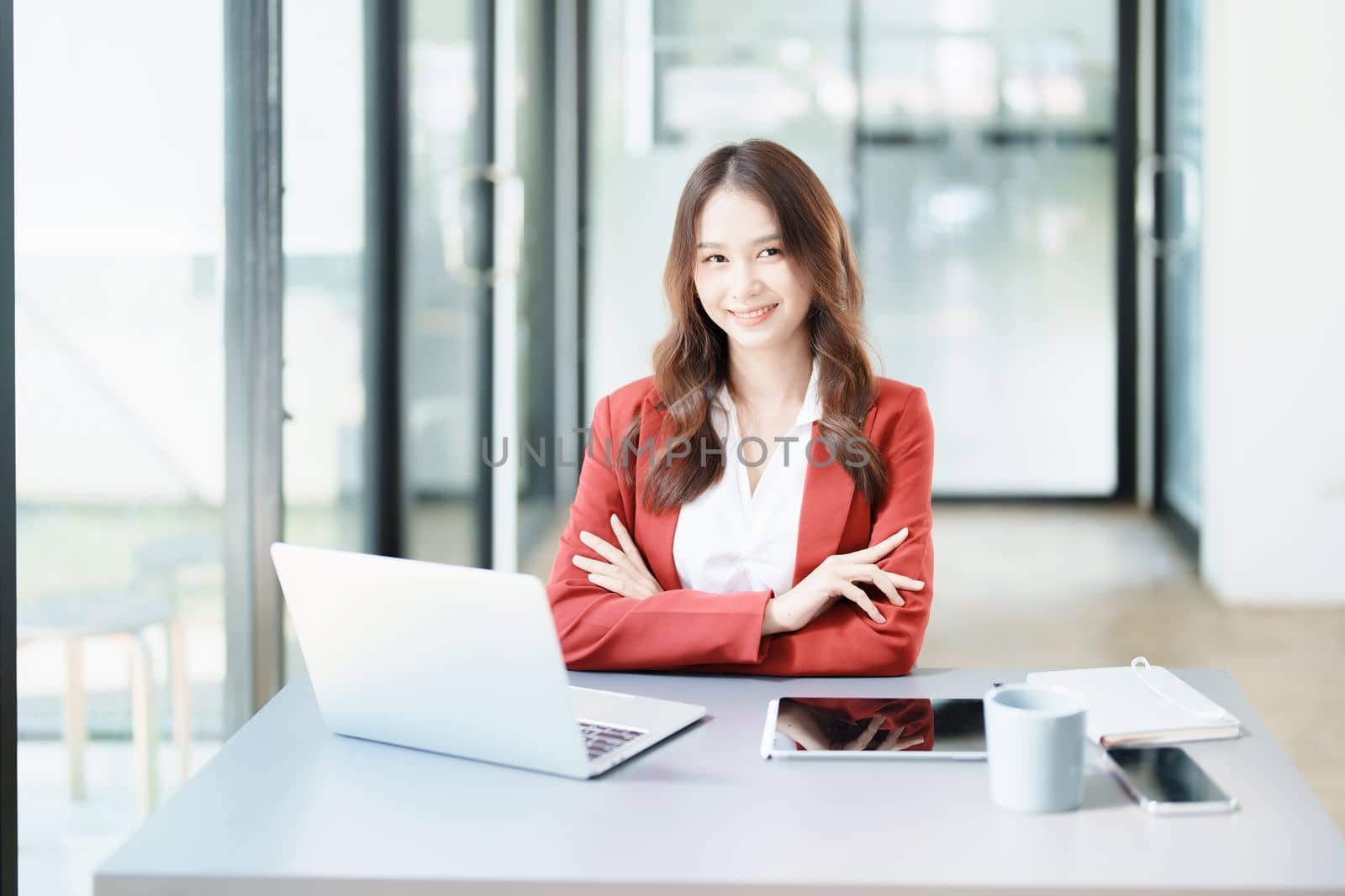 Portrait of a woman business owner showing a happy smiling face as he has successfully invested her business using computers and financial budget documents at work by Manastrong