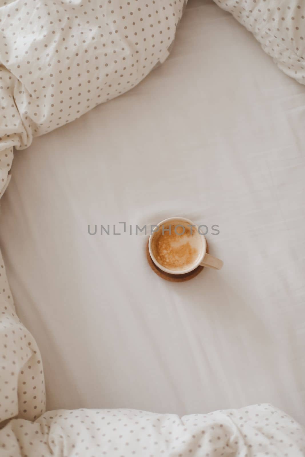 Cozy unmade messy bed with a coffee cup in the morning, breakfast in bed.