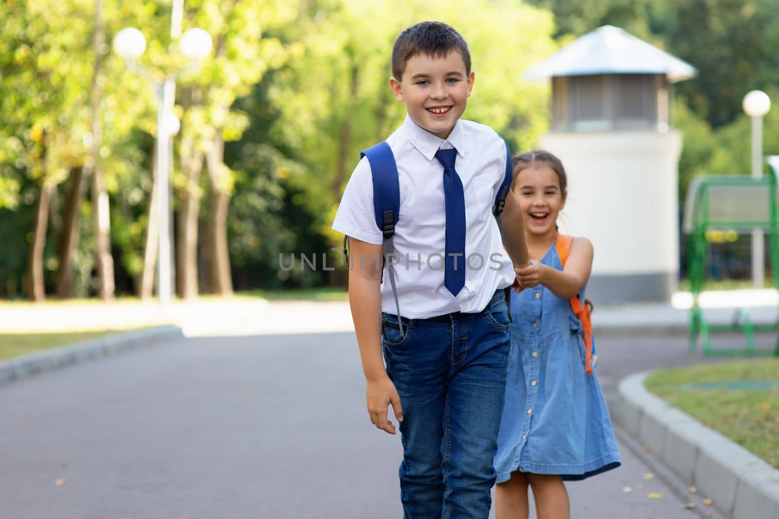 Cheerful schoolchildren boy and girl in a white shirt in the morning on a sunny day against the background of a street