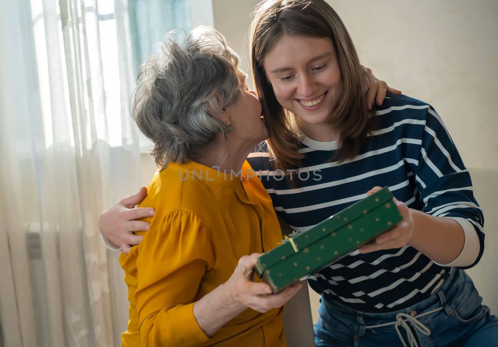 Two women, relatives, happily spend time together, grandmother and daughter give gifts to each other for the holidays, make pleasant surprises, love and emotional bonding inside the family.