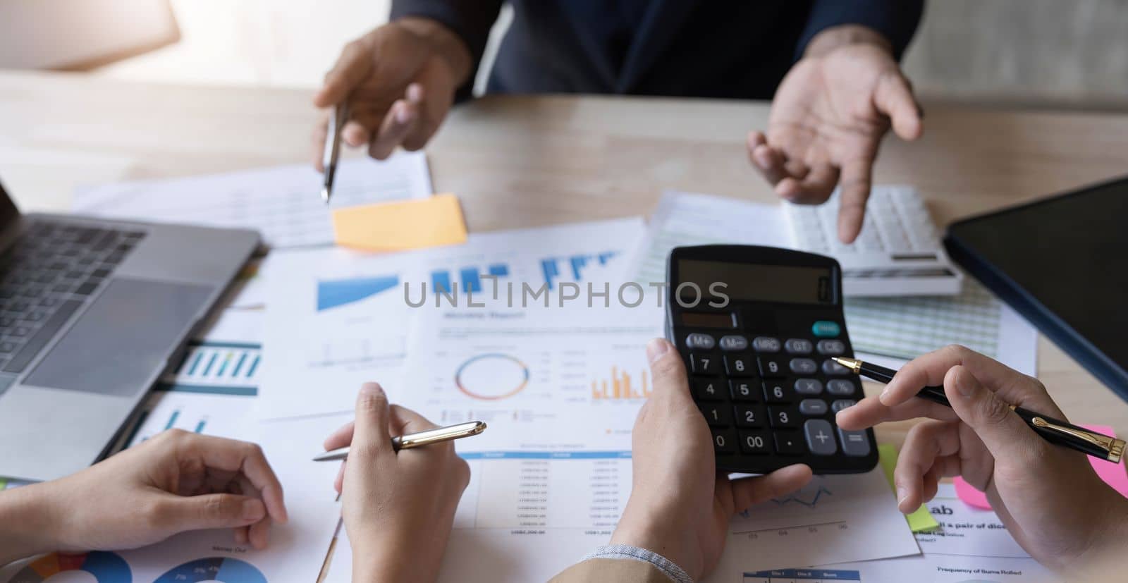 Business People Meeting using laptop computer,calculator,notebook,stock market chart paper for analysis Plans to improve quality next month. Conference Discussion Corporate Concept...