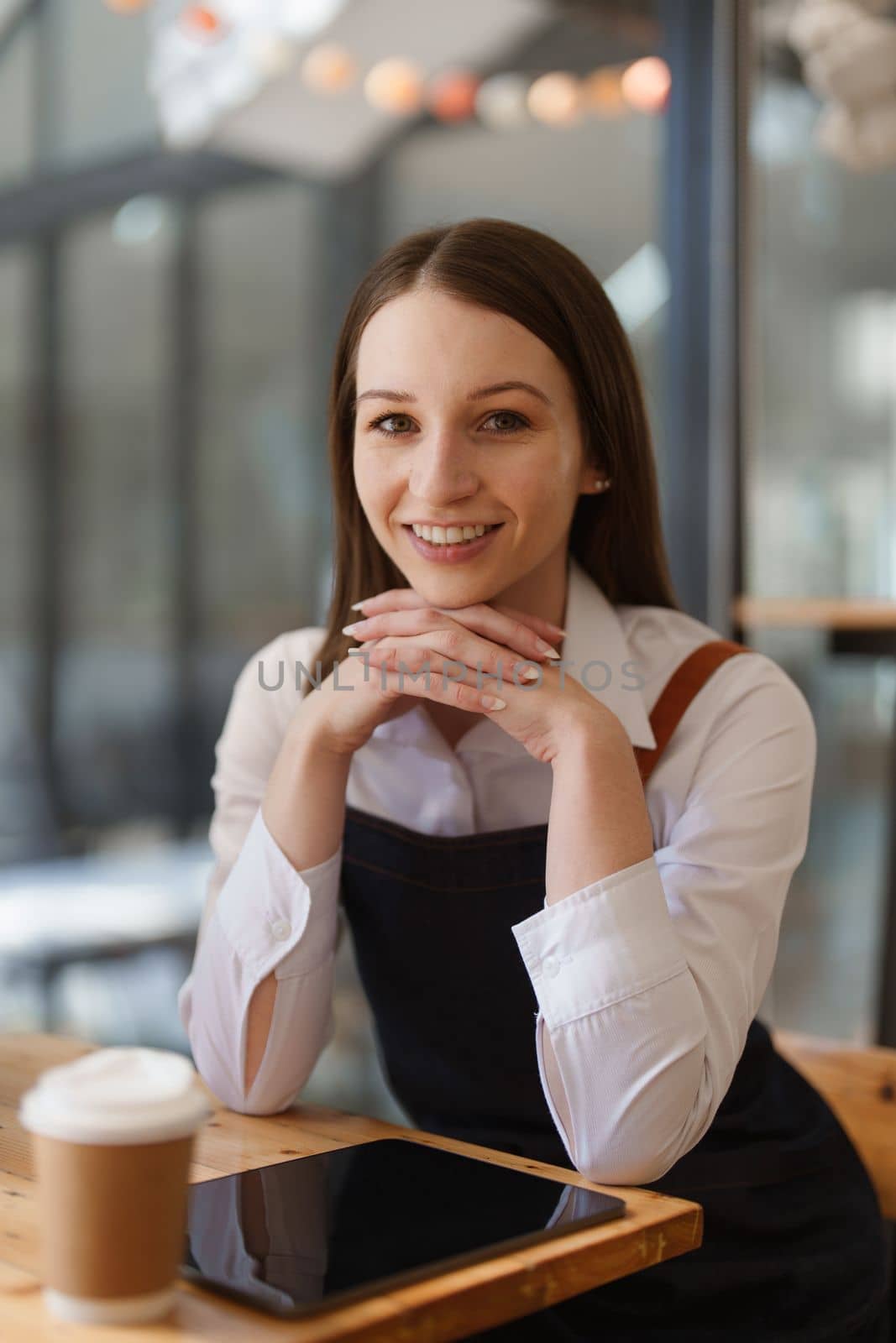 Young Female manager in restaurant with tablet. Woman coffee shop owner with open sign. Small business concept.