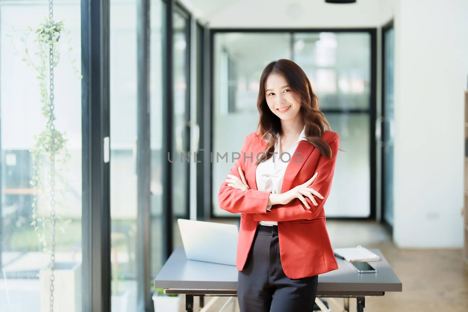 Portrait of a woman business owner showing a happy smiling face as he has successfully invested her business using computers and financial budget documents at work.