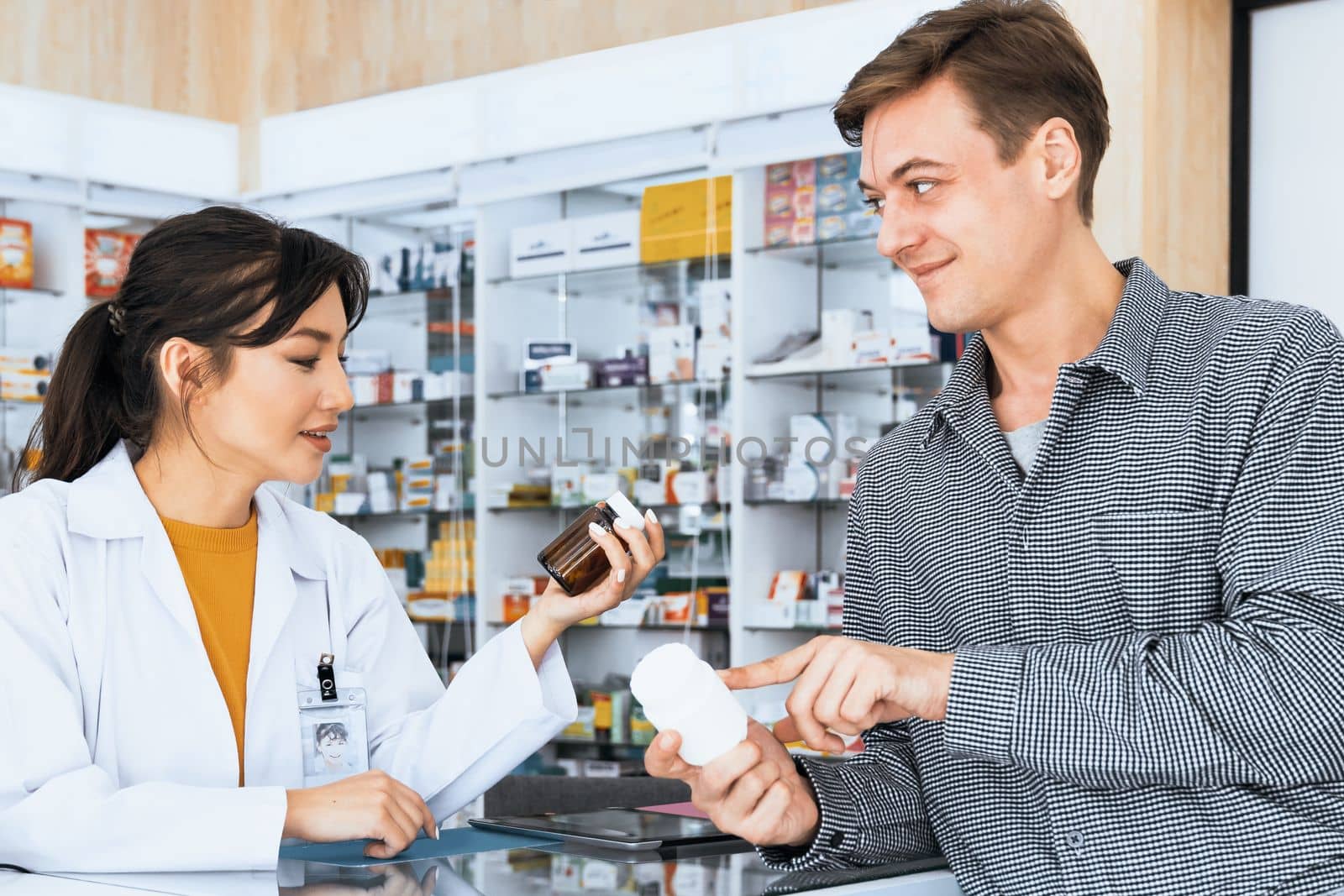 Professional pharmacist advise or explain property of qualified medical product to customer in pharmacy, druggist answer to client healthcare inquiry, medical service and consultation concept.