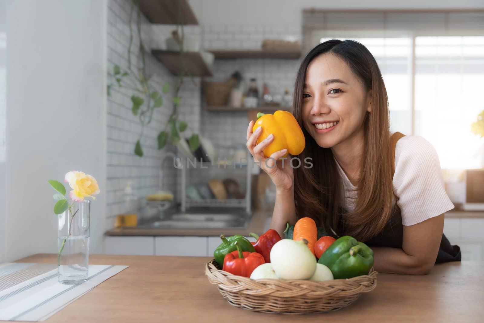 Portrait of young happy woman wearing appron standing in the kitchen room, prepares cooking healthy food from fresh vegetables and fruits...