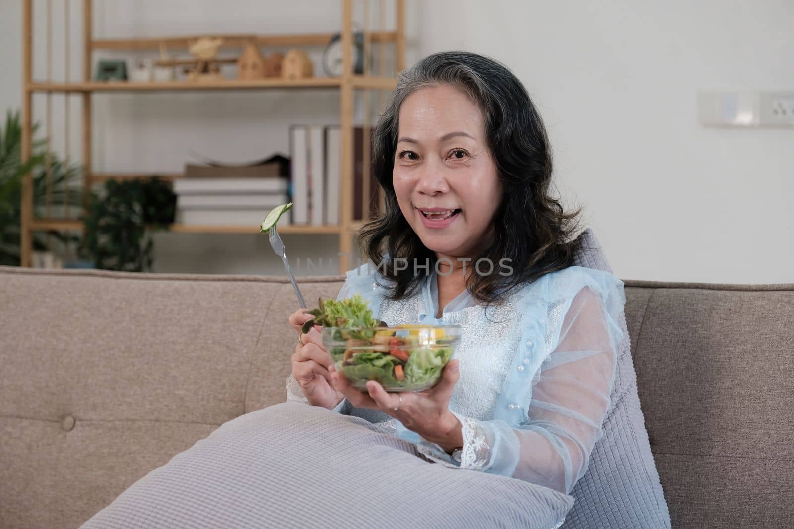 Happy old asian woman eating fresh green salad. Senior woman good healthy at home. Exercise and healthy diet concept by itchaznong