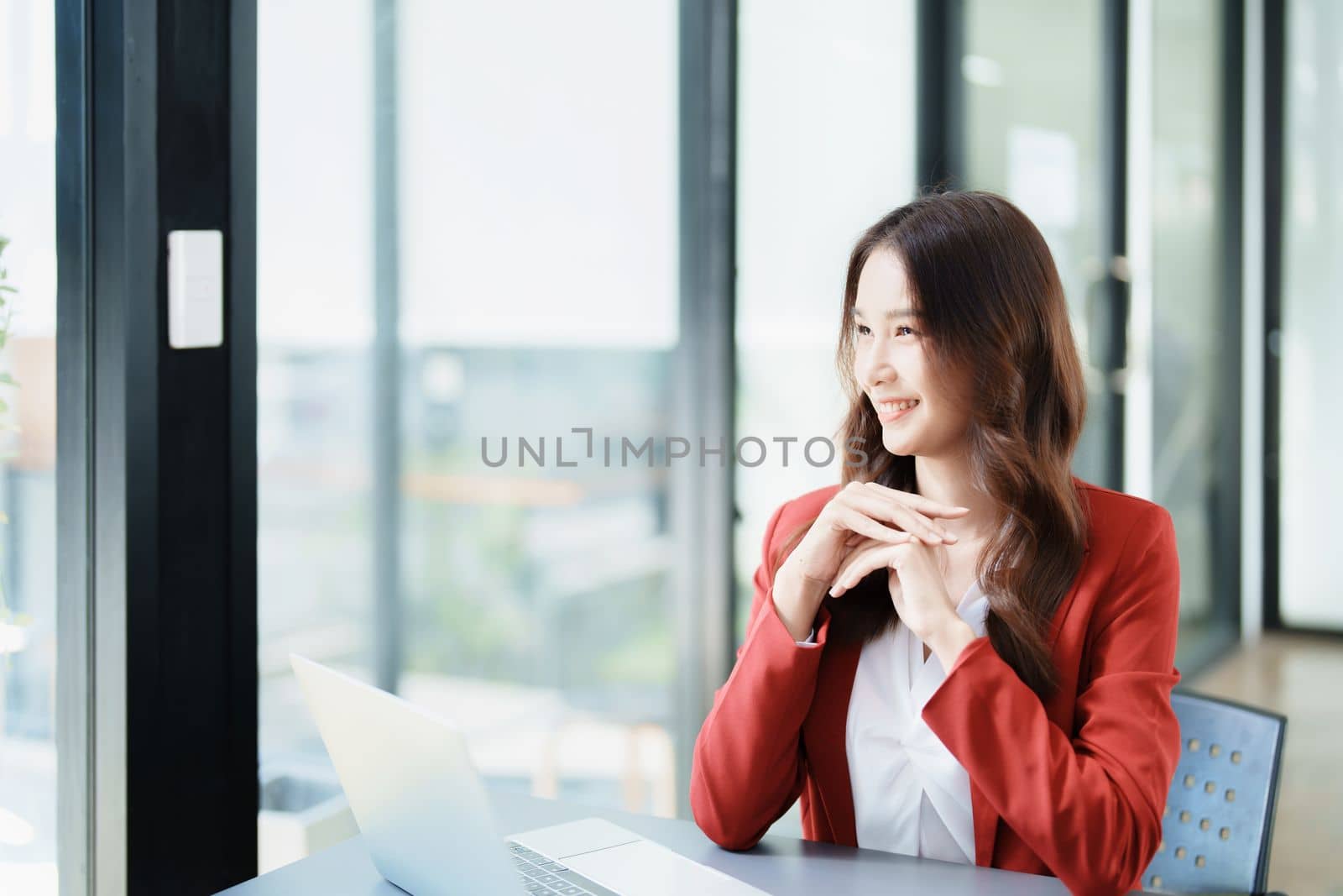 Portrait of a woman business owner showing a happy smiling face as he has successfully invested her business using computers and financial budget documents at work by Manastrong
