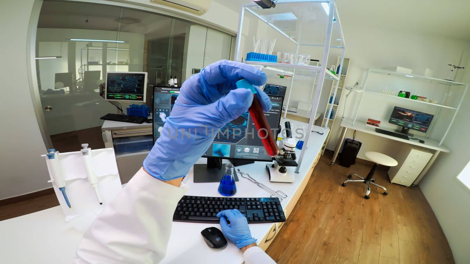 POV of scientist analysing blood sample from test tube by DCStudio