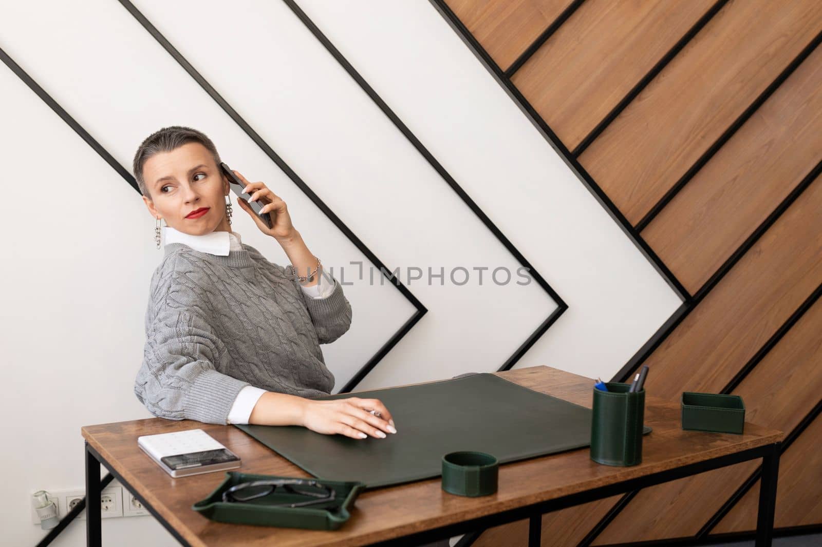 Business woman with short haircut talking on the phone in the office.