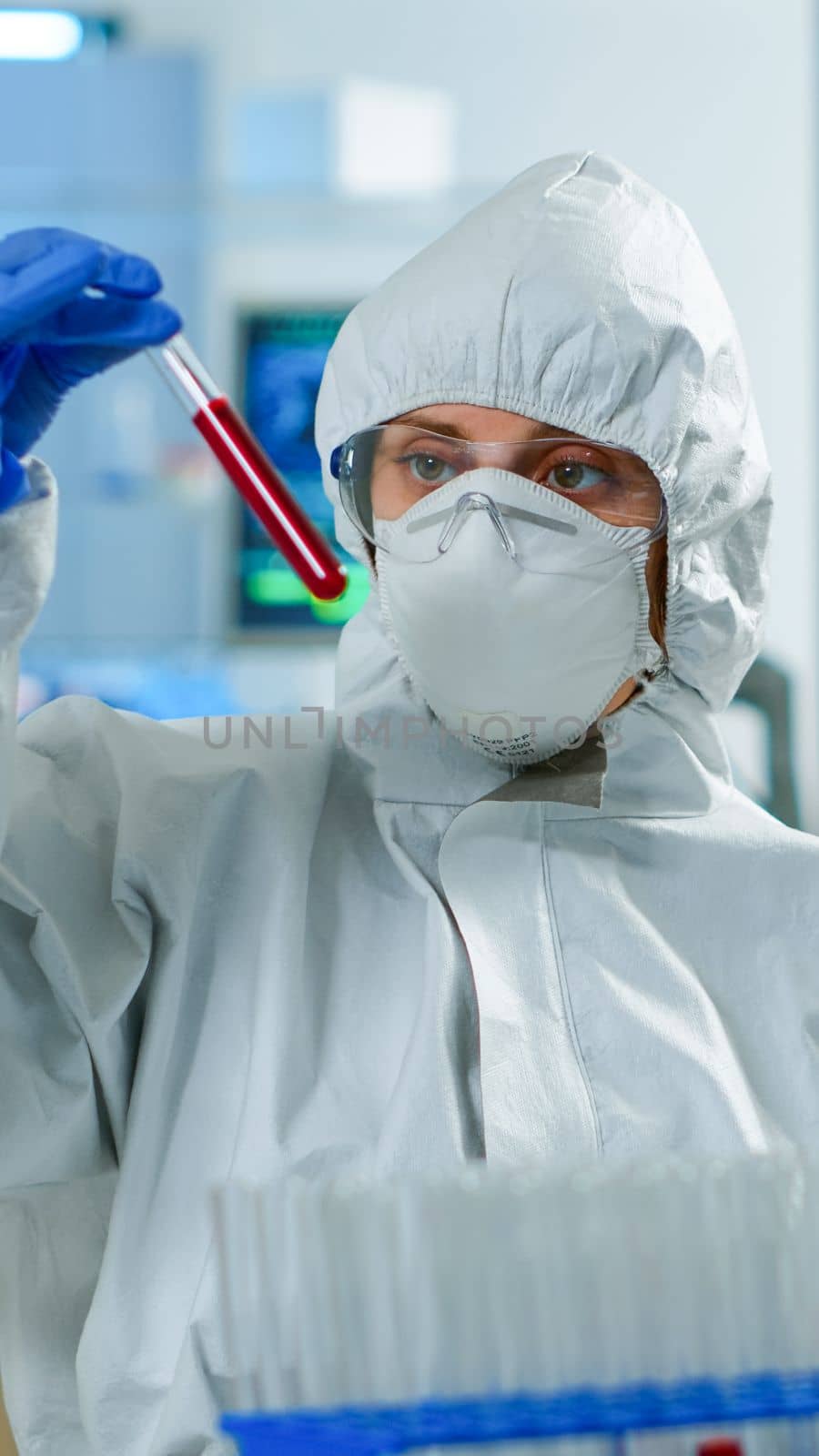 Neurologist with ppe suit working at vaccine development analysing blood sample in equipped laboratory typing on pc. Team examining virus evolution using high tech for research in treatment for covid19