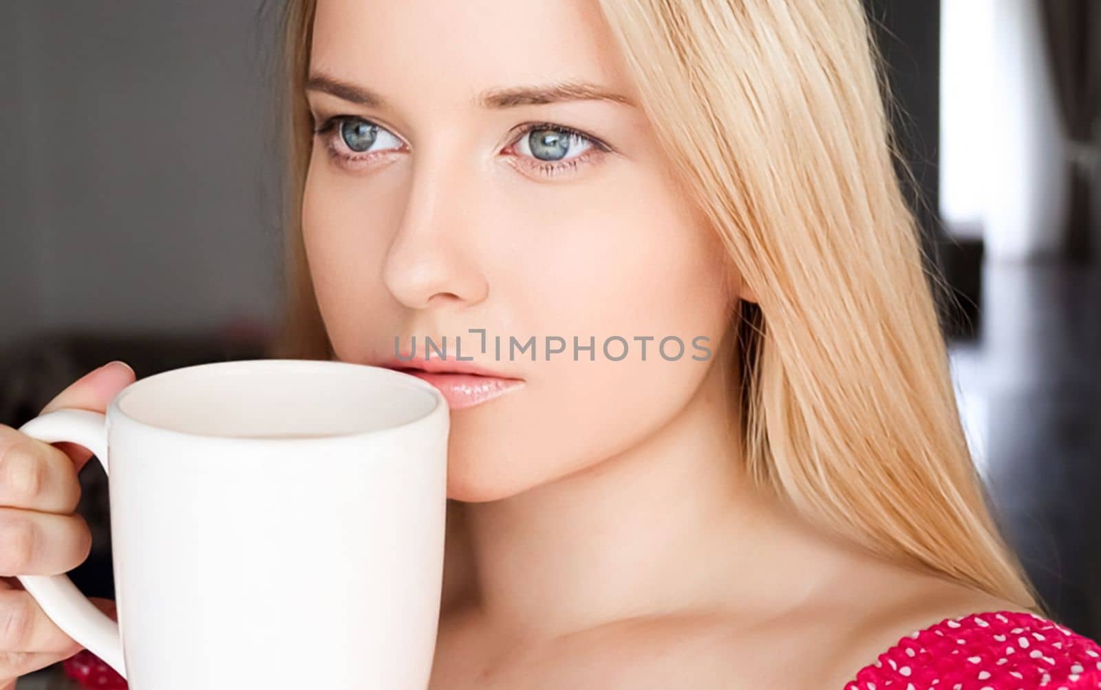 Beautiful blonde woman having a cup of tea in the morning at home.