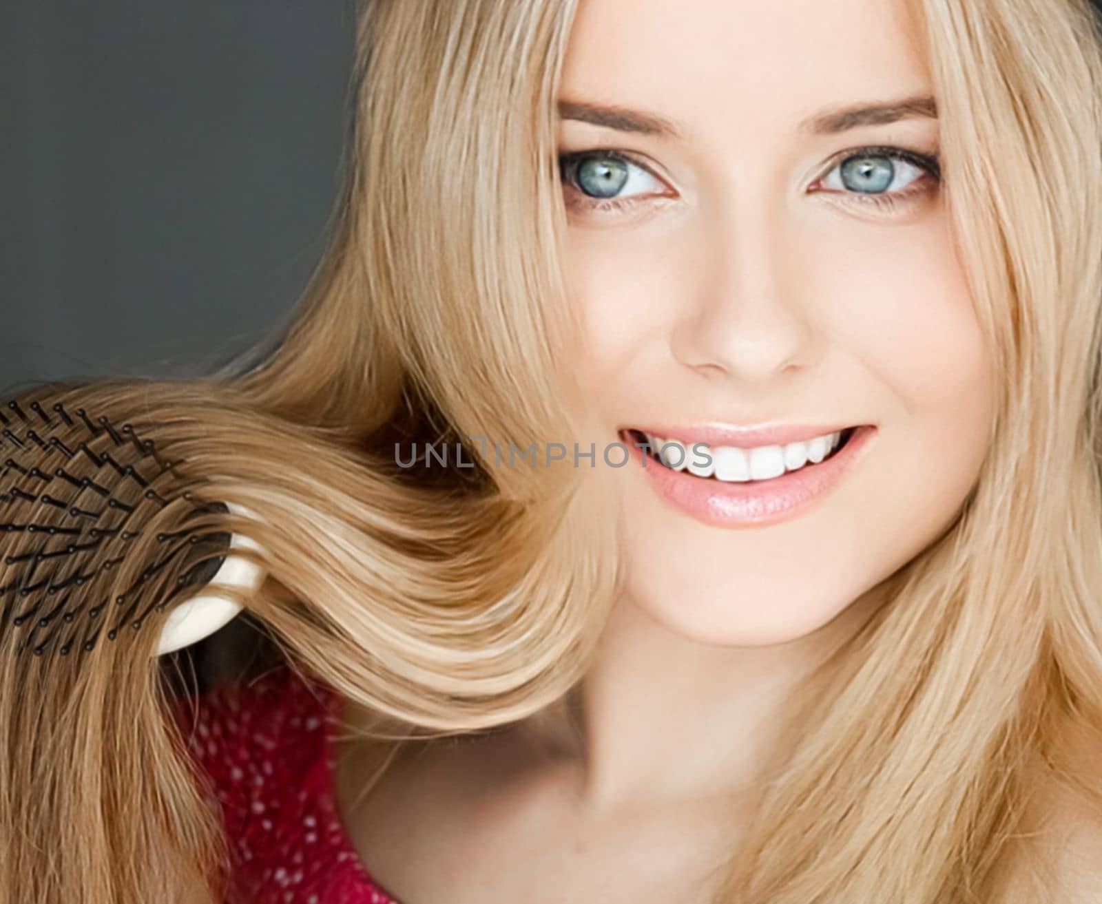 Beautiful happy woman combing her long blond hair.