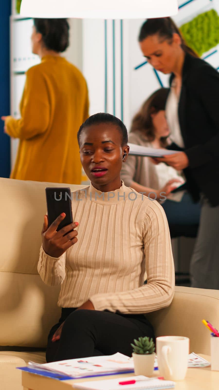 Tired black woman talking with colleague using video call holding smartphone by DCStudio