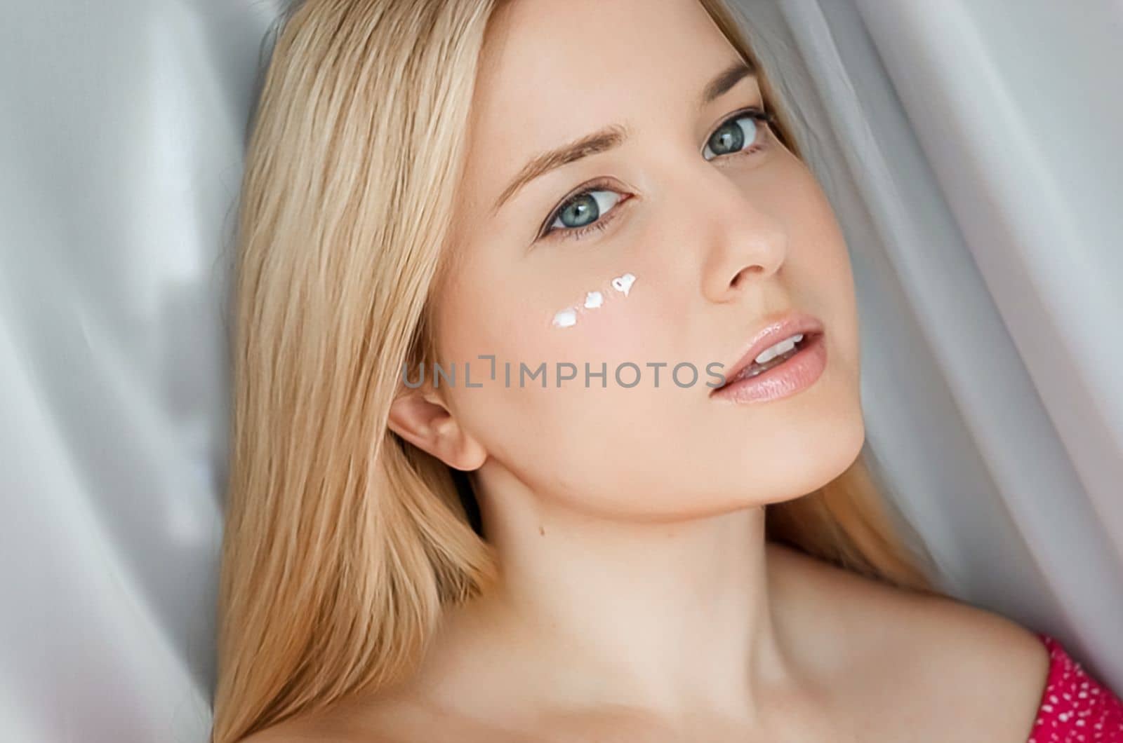 Beautiful woman with skincare cream on her face.