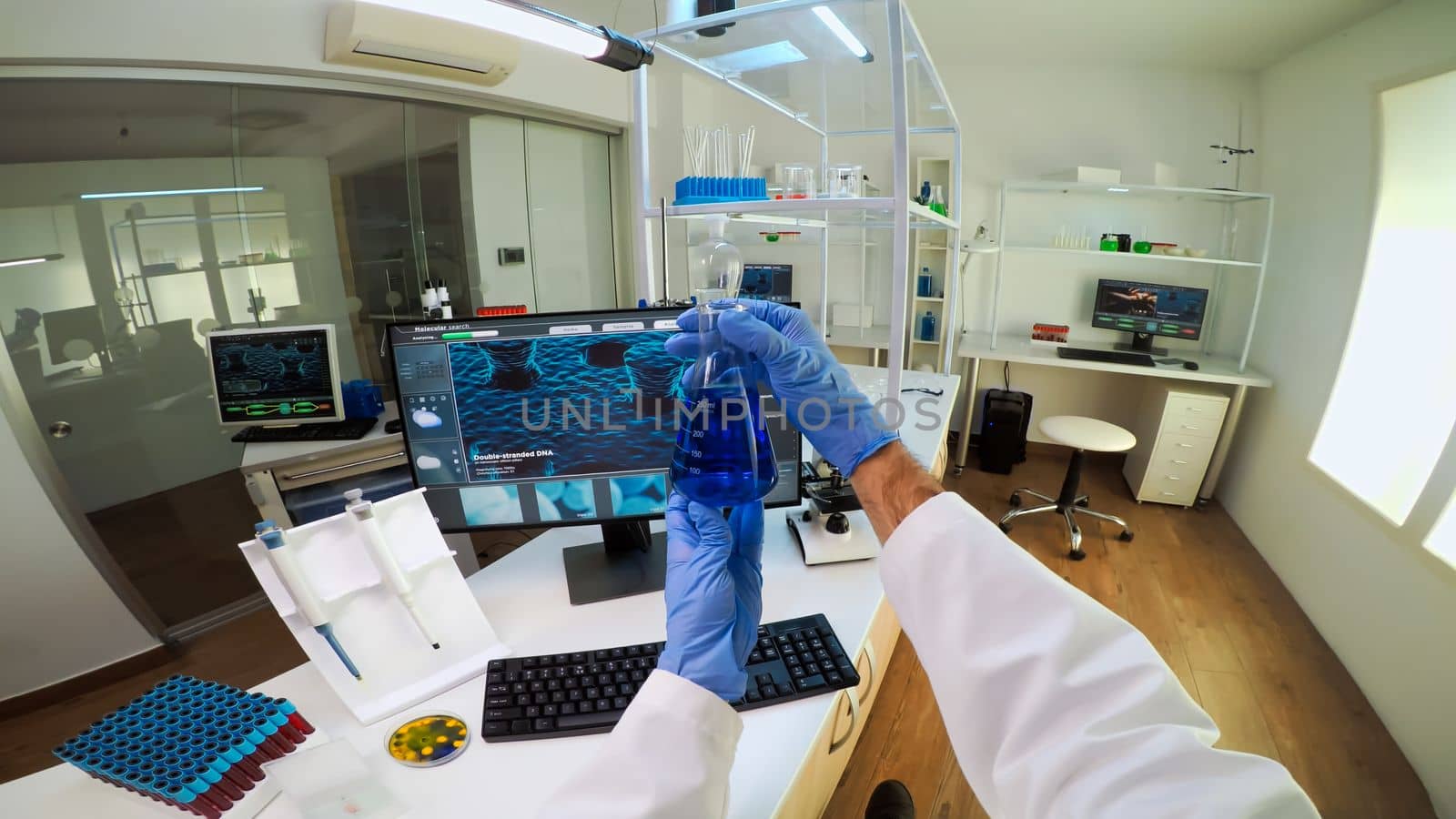 POV of medical scientist working with DNA scan image in modern equipped lab holding test tube with sample. Team examining vaccine evolution using high tech and chemistry tools for vaccine development