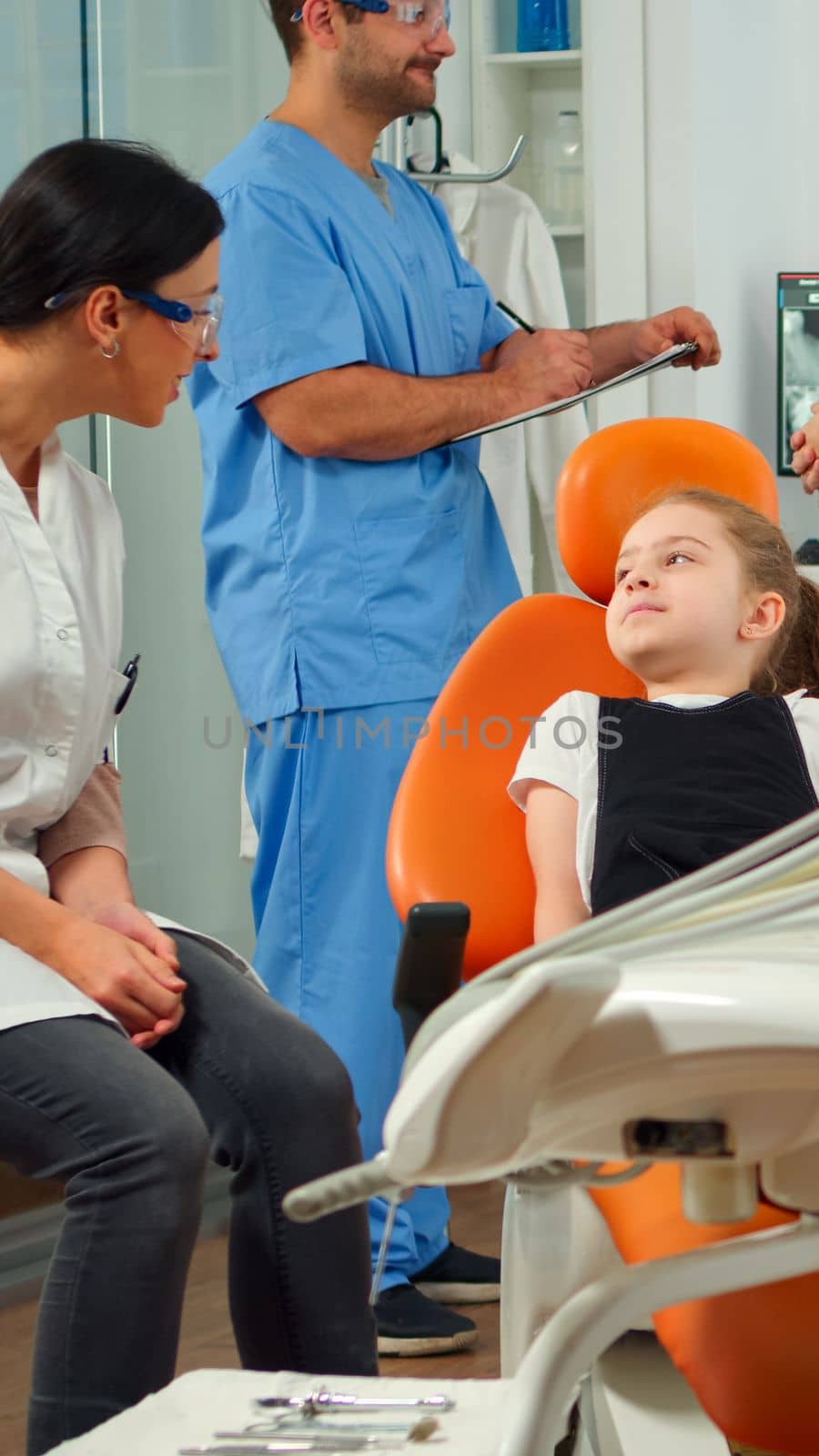 Man nurse inviting kid patient in consultation dental room by DCStudio