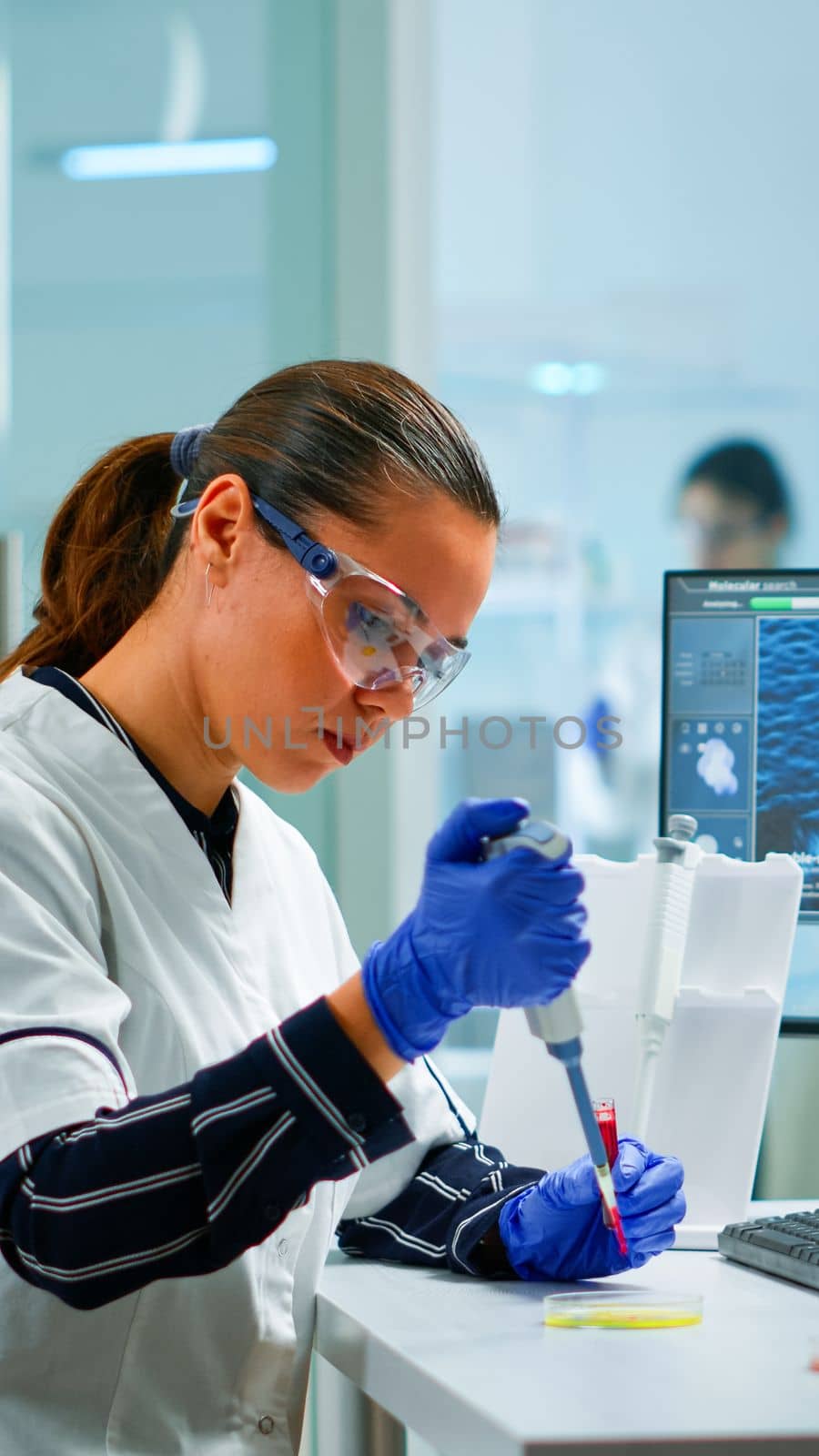 Scientist in modern equipped medical laboratory examinining drug discovery with micropipette. Medical stuff examining vaccine evolution using high tech and technology researching treatment, development against covid19