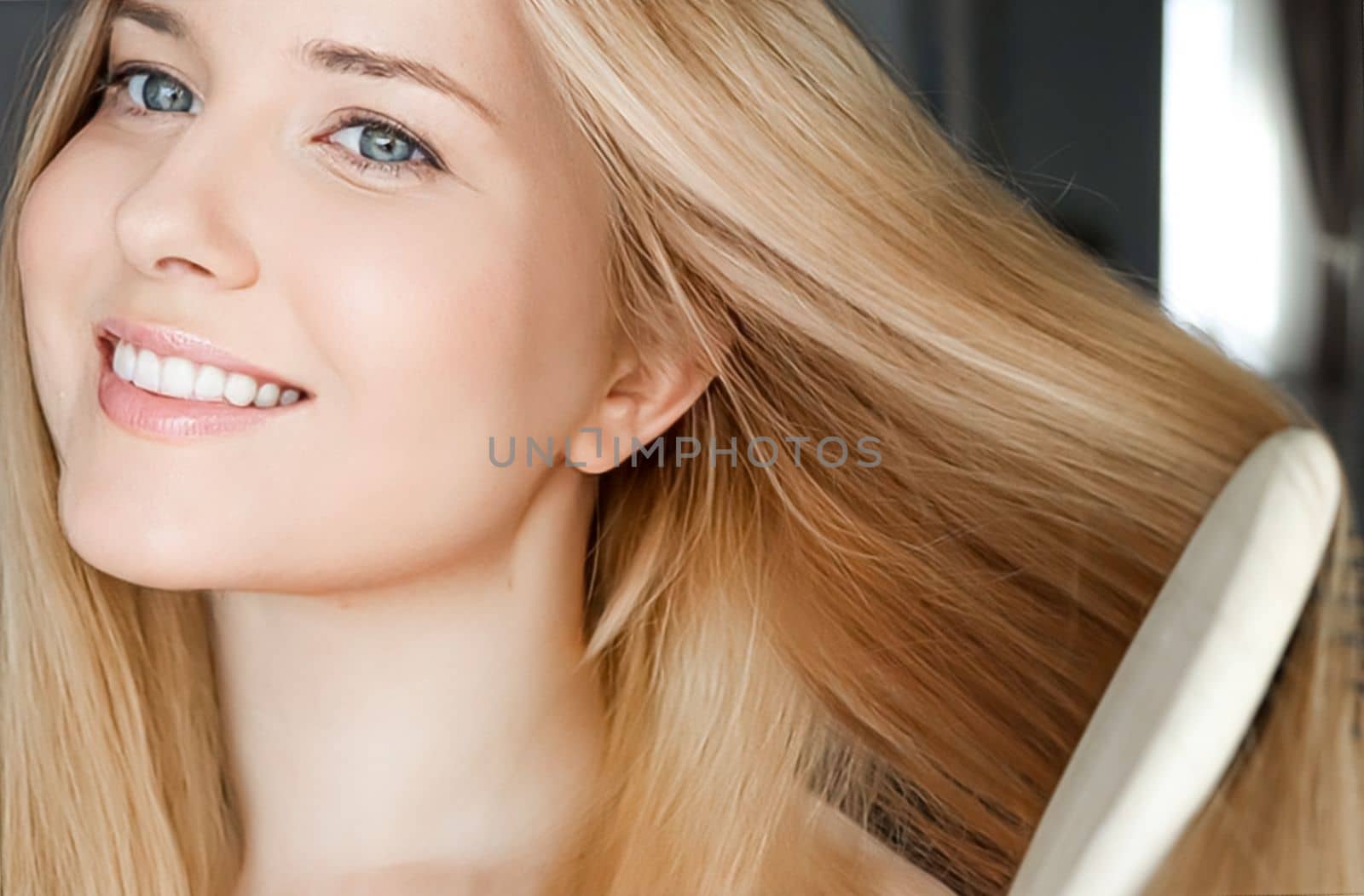 Beautiful happy woman combing her long blond hair.