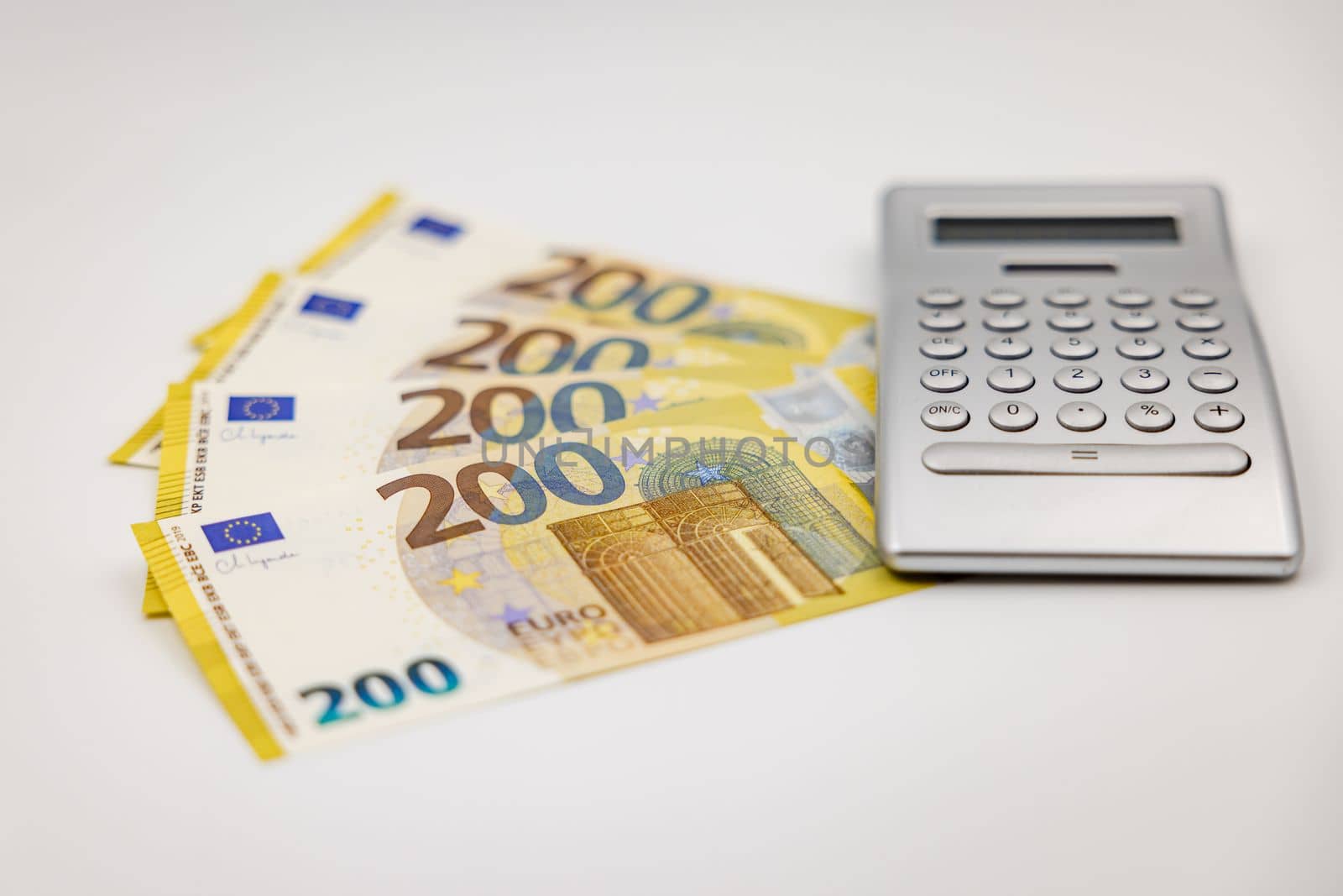 200 Euro banknotes and calculator photographed from the side with shallow depth of field