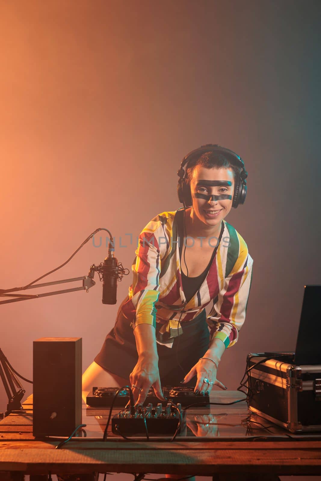 Smiling woman dj mixing sounds at turntables, using audio instrument and equipment to play techno music. Happy musician with crazy make up using electronics to do musical performance.