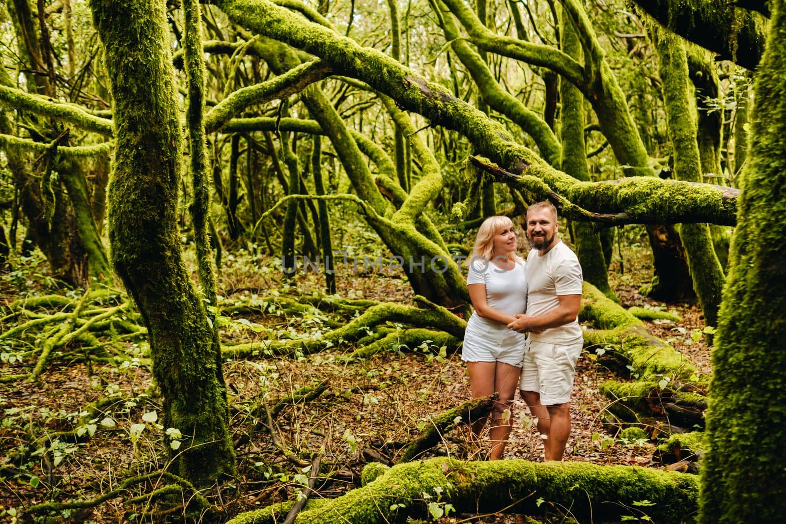 Two people, a man and a woman in white clothes, are standing in an old forest on the island of LA Gomera. The Canary Islands. Spain.