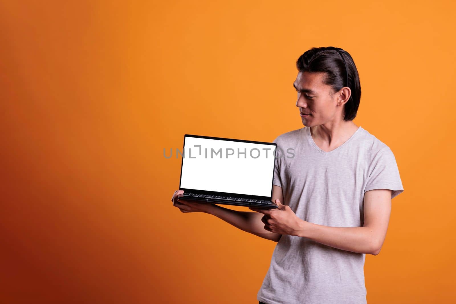 Confident asian man showing laptop with white blank screen by DCStudio