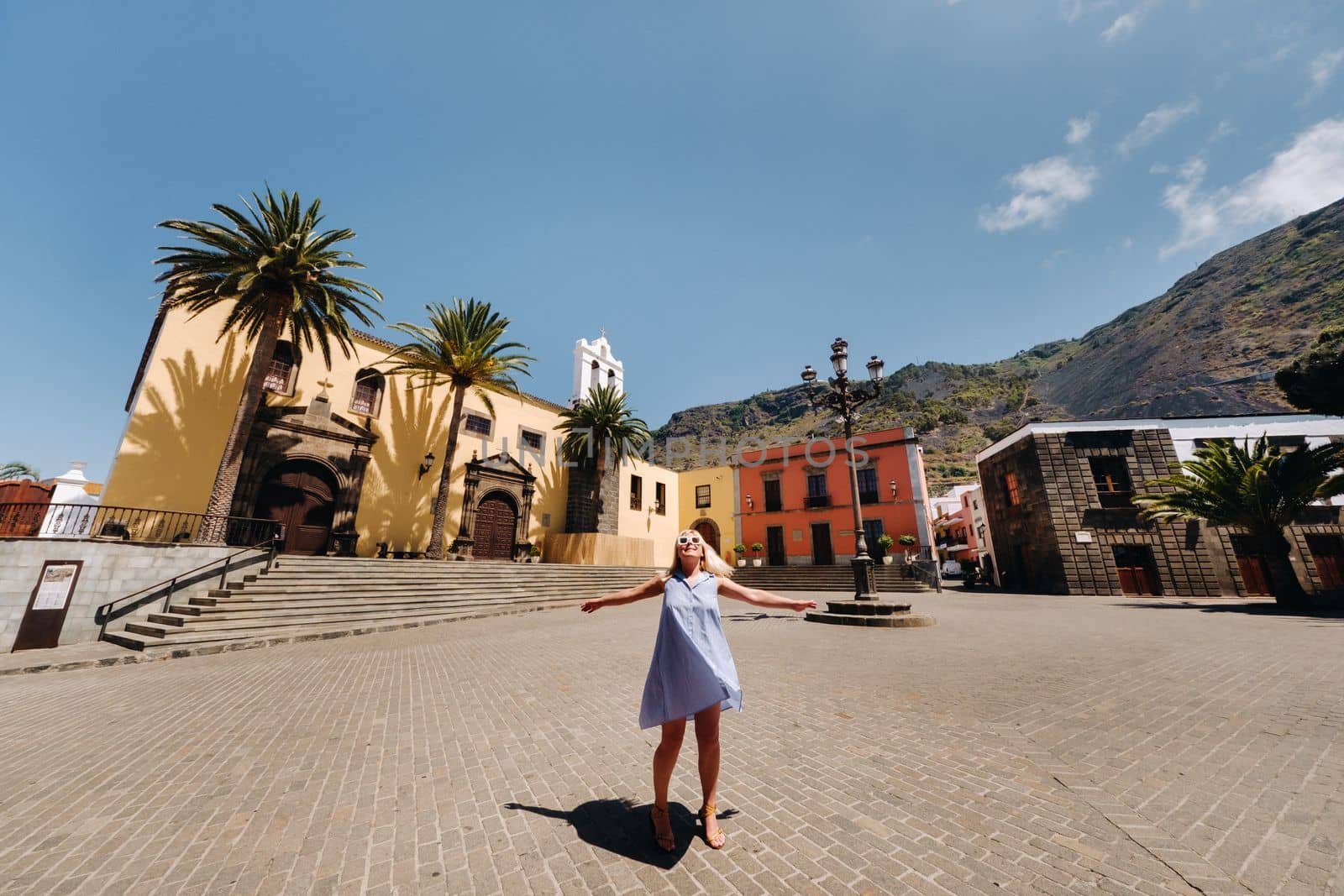 A girl in a blue dress walks through the Old Town of Garachico on the island of Tenerife on a sunny day. Spain.