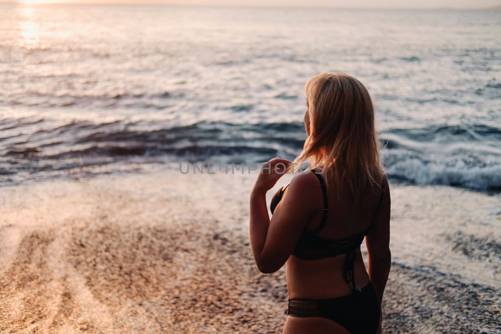 A girl at sunset on the beach near the cliffs of Acantilados de Los Gigantes at sunset, Tenerife, Spain