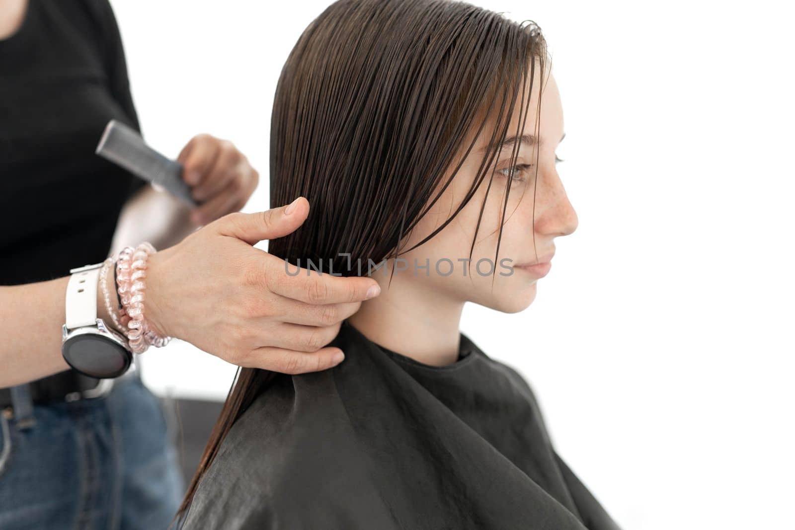 Hairdresser preparing hair of girl for haircut. Female child in beauty salon