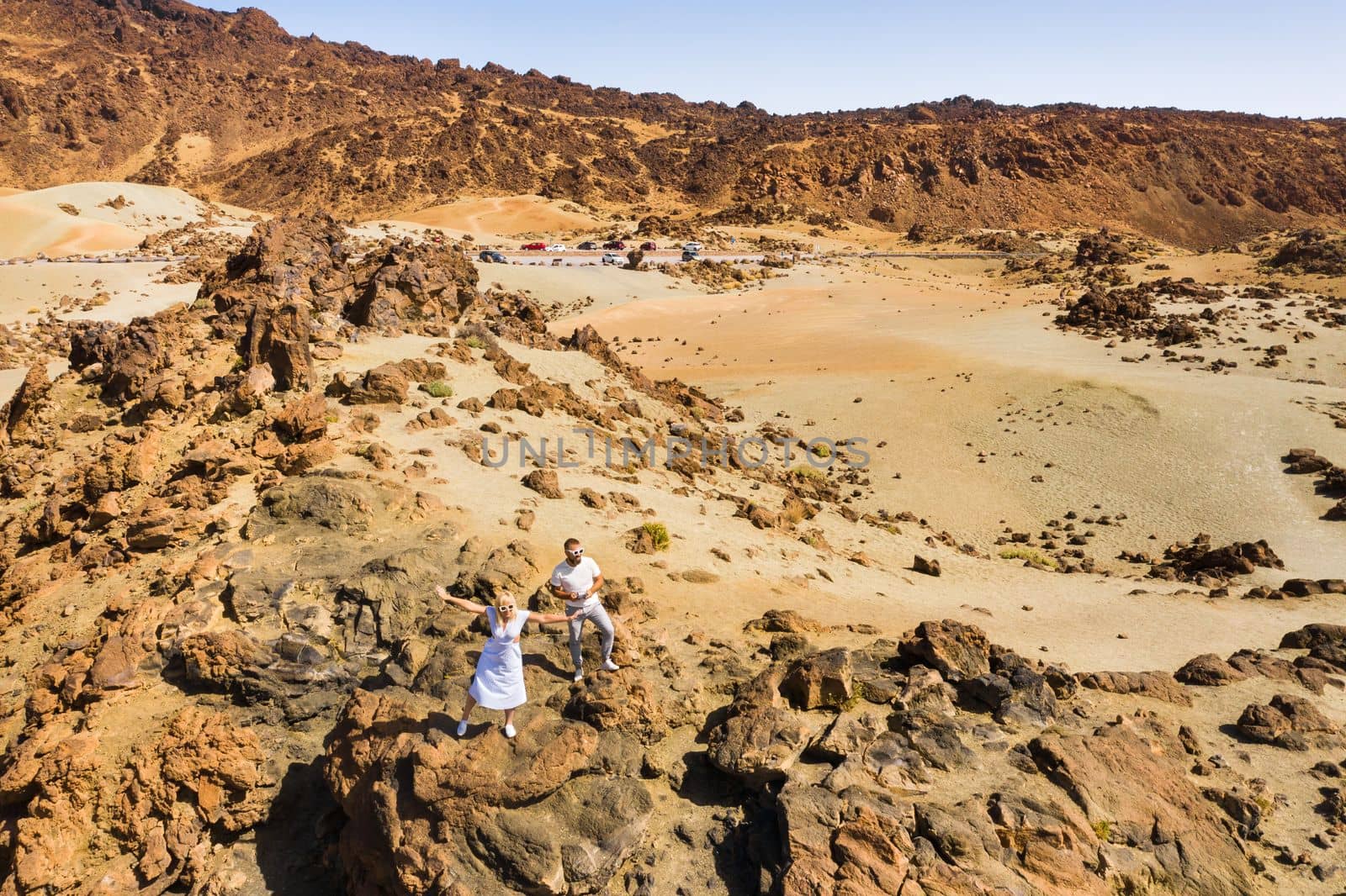 A married couple is standing in the crater of the Teide volcano. Desert landscape in Tenerife. Teide National Park. Tenerife, Spain by Lobachad