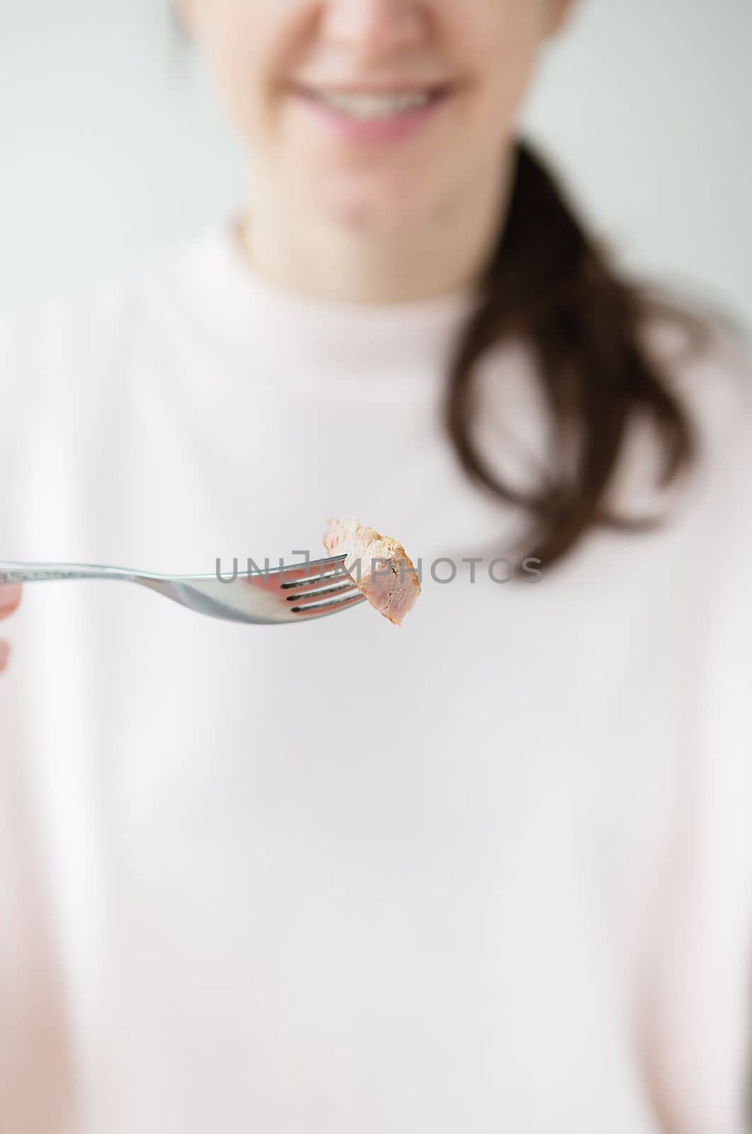 The girl holds a piece of tuna in her hand on a fork. Asian food. Close-up. Vertical photo