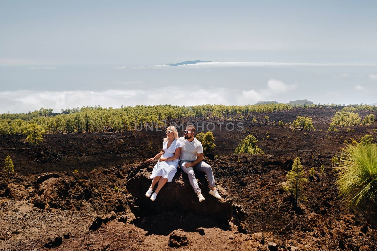 A couple in love is sitting on the slope of the Teide volcano. Desert landscape in Tenerife. Teide National Park. Tenerife, Spain.